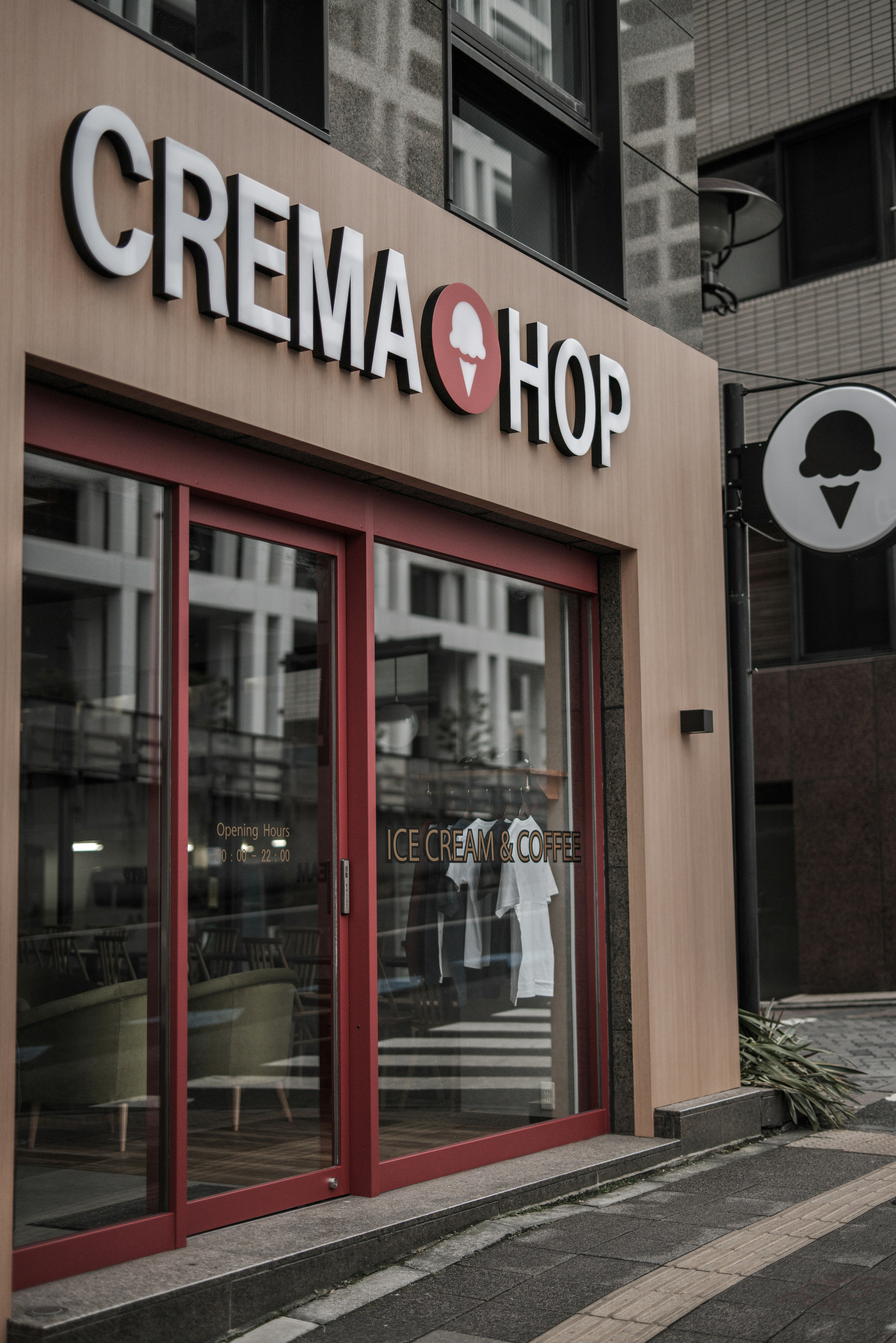 Exterior view of Crema Hop shop with red door and logo