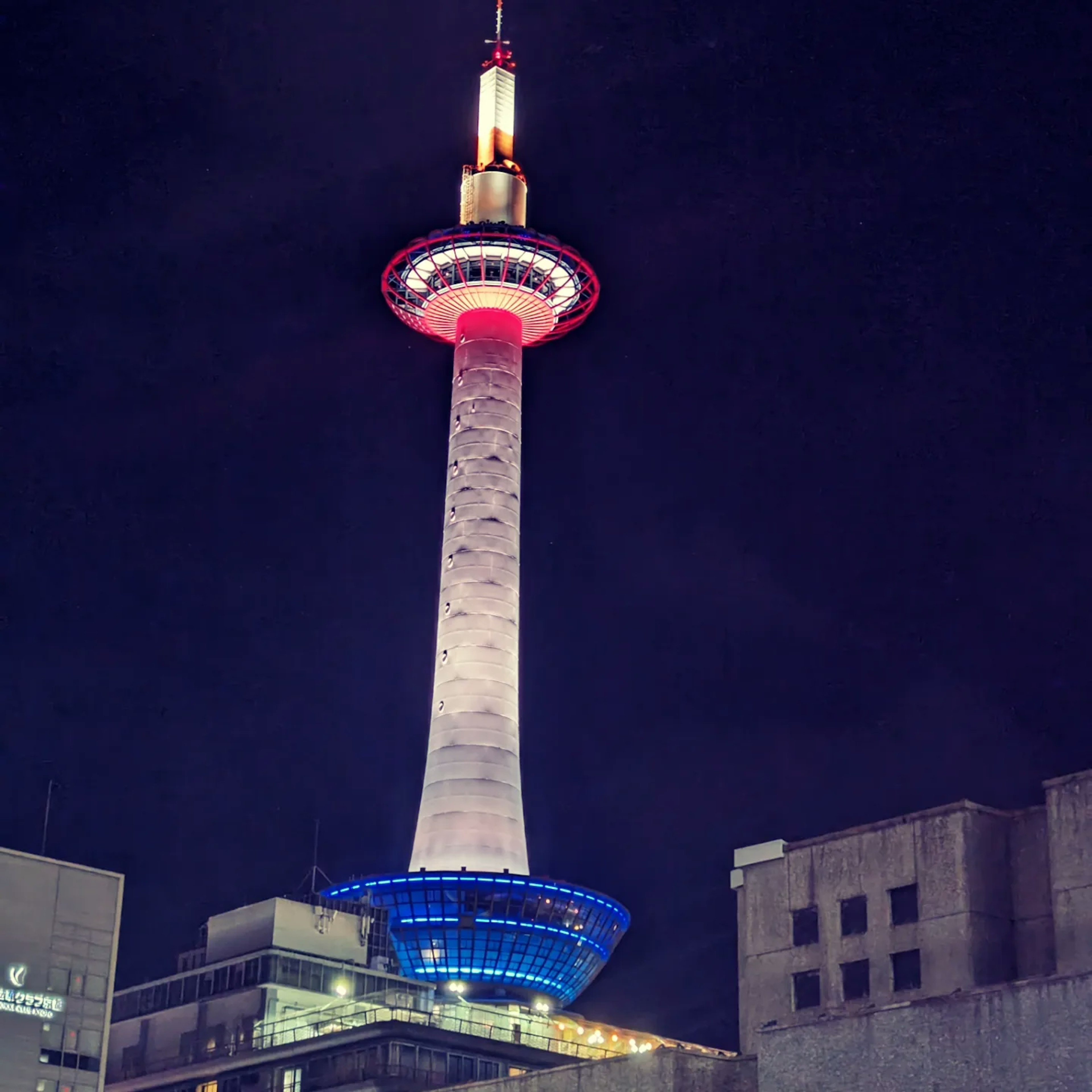 Torre de Kioto iluminada por la noche con luces rojas y azules