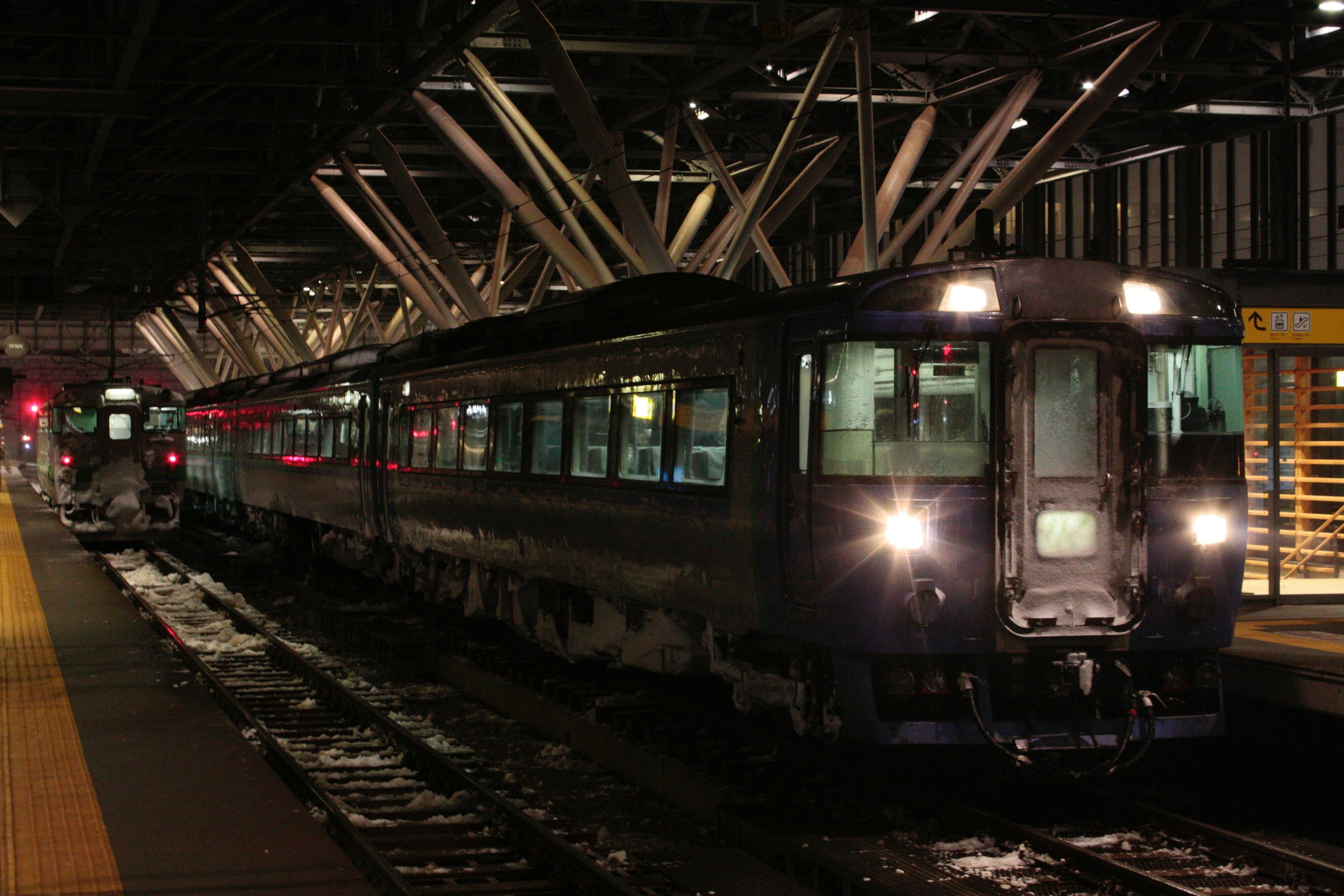 夜の駅で停車中の列車とその周囲の構造物