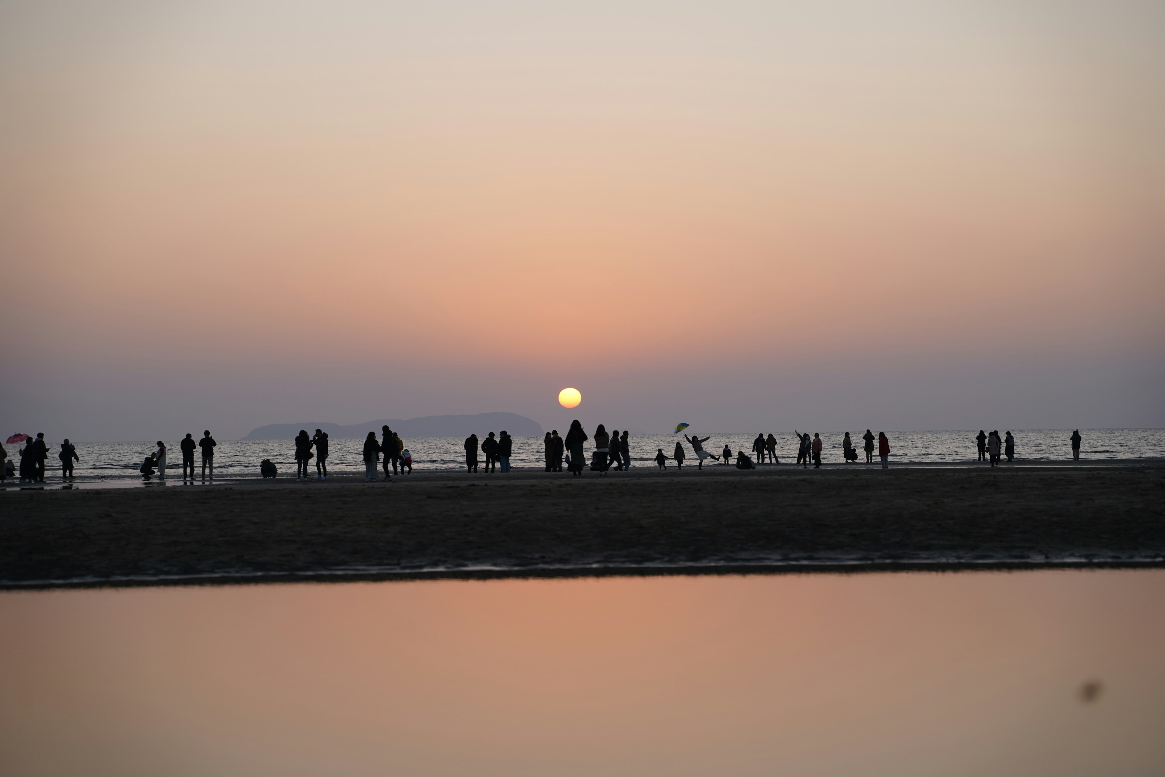 Silhouetten von Personen am Strand mit Sonnenuntergang im Hintergrund