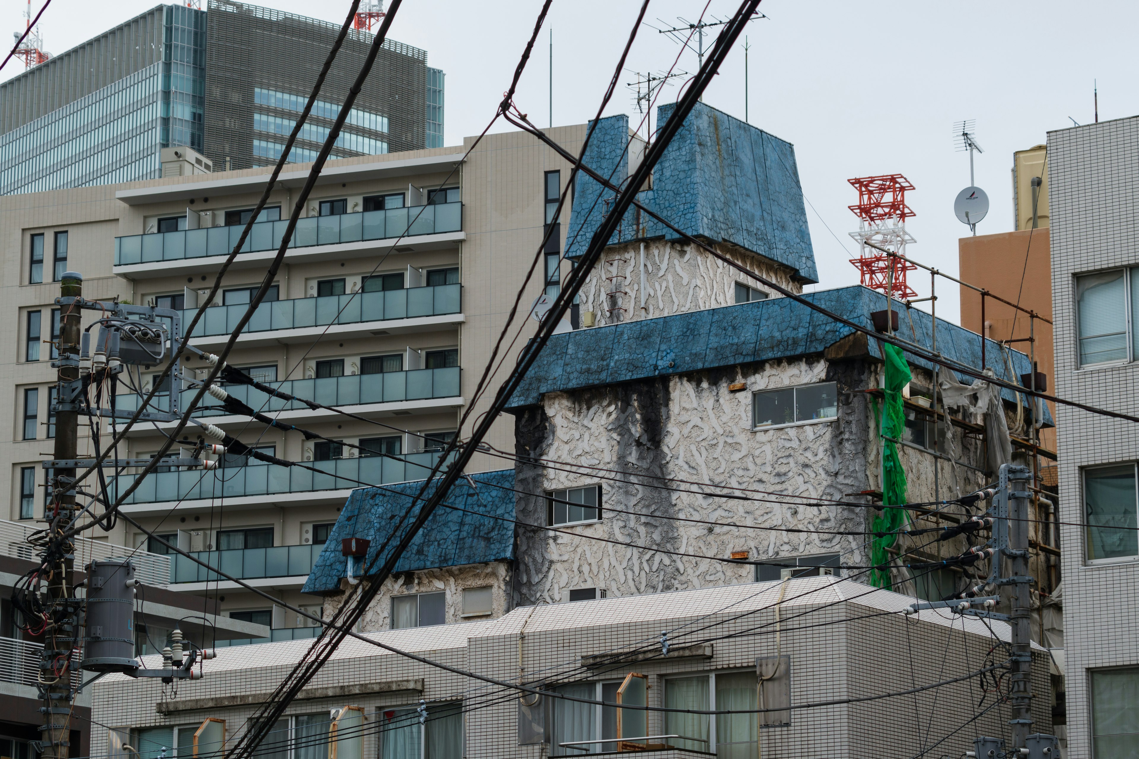 An old building with a blue roof adjacent to modern high-rise buildings