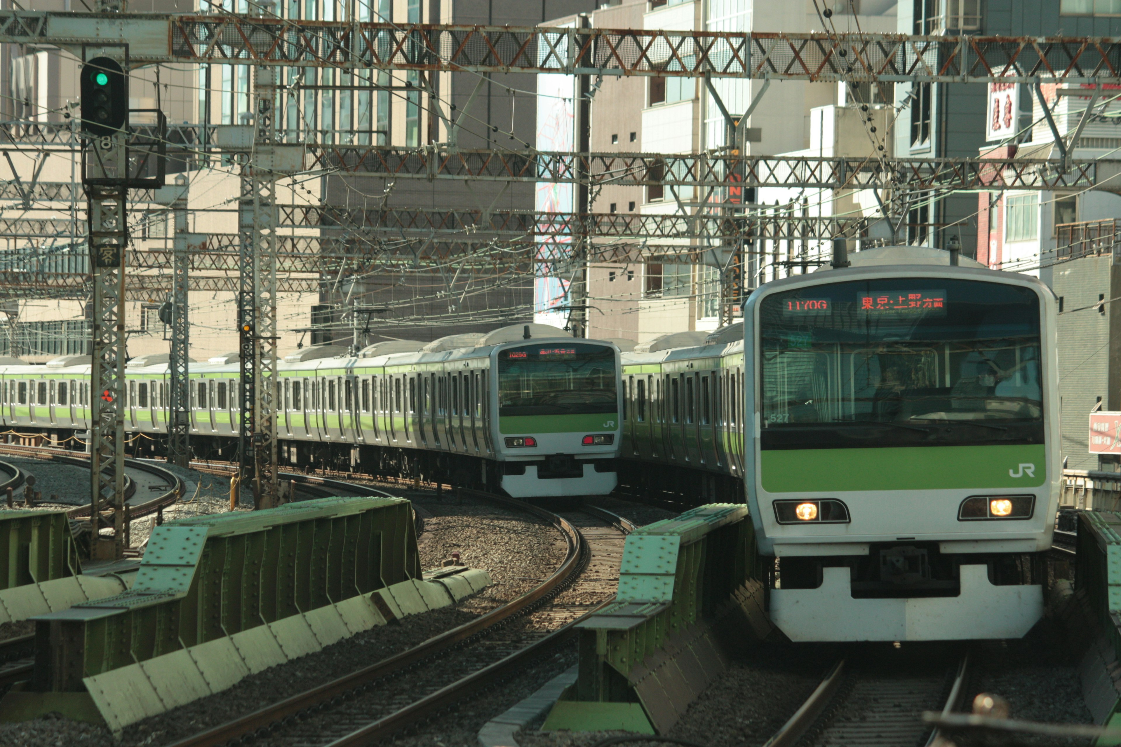 Scena ferroviaria urbana con treni verdi che si incrociano