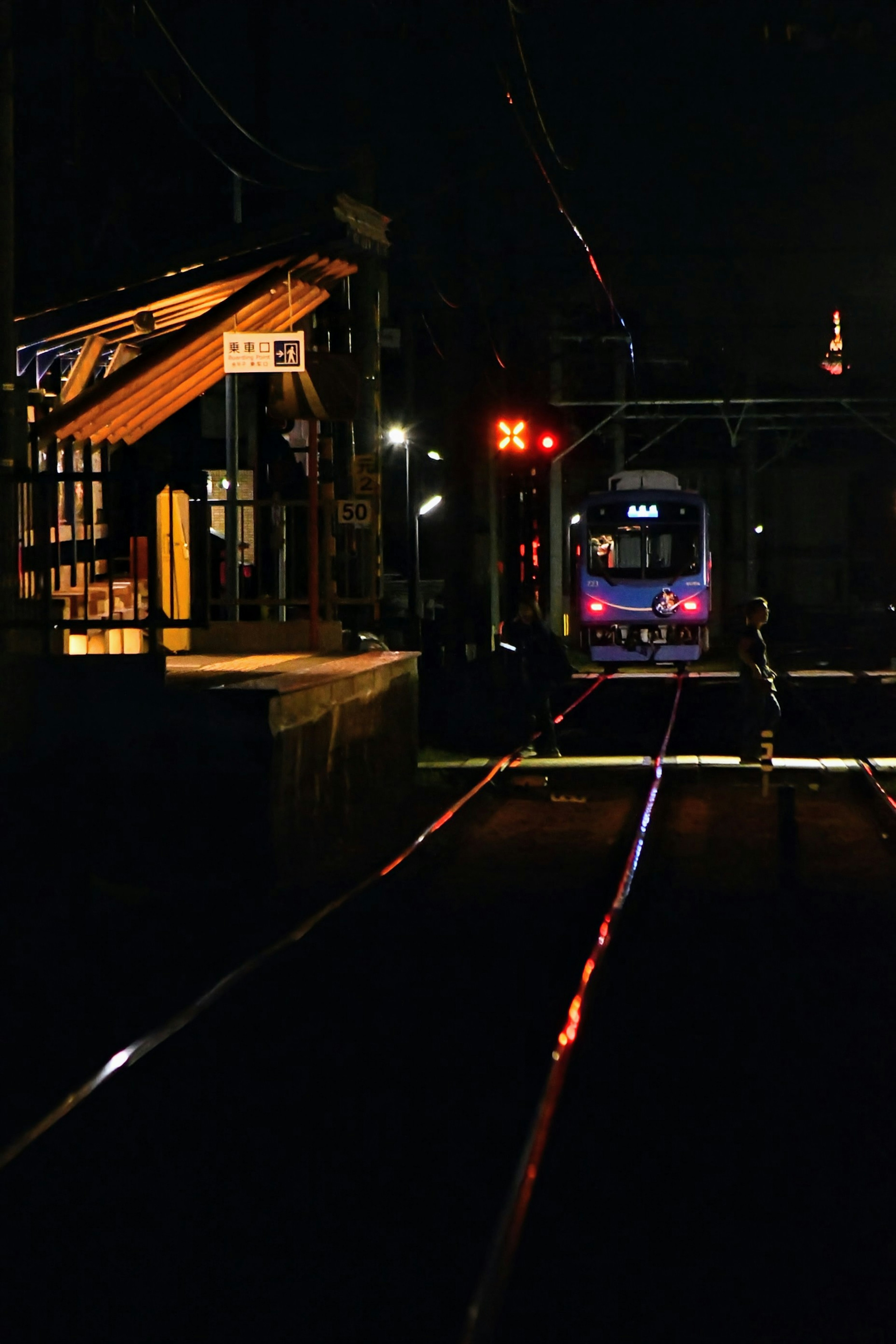 Tren detenido en una estación por la noche con vías iluminadas