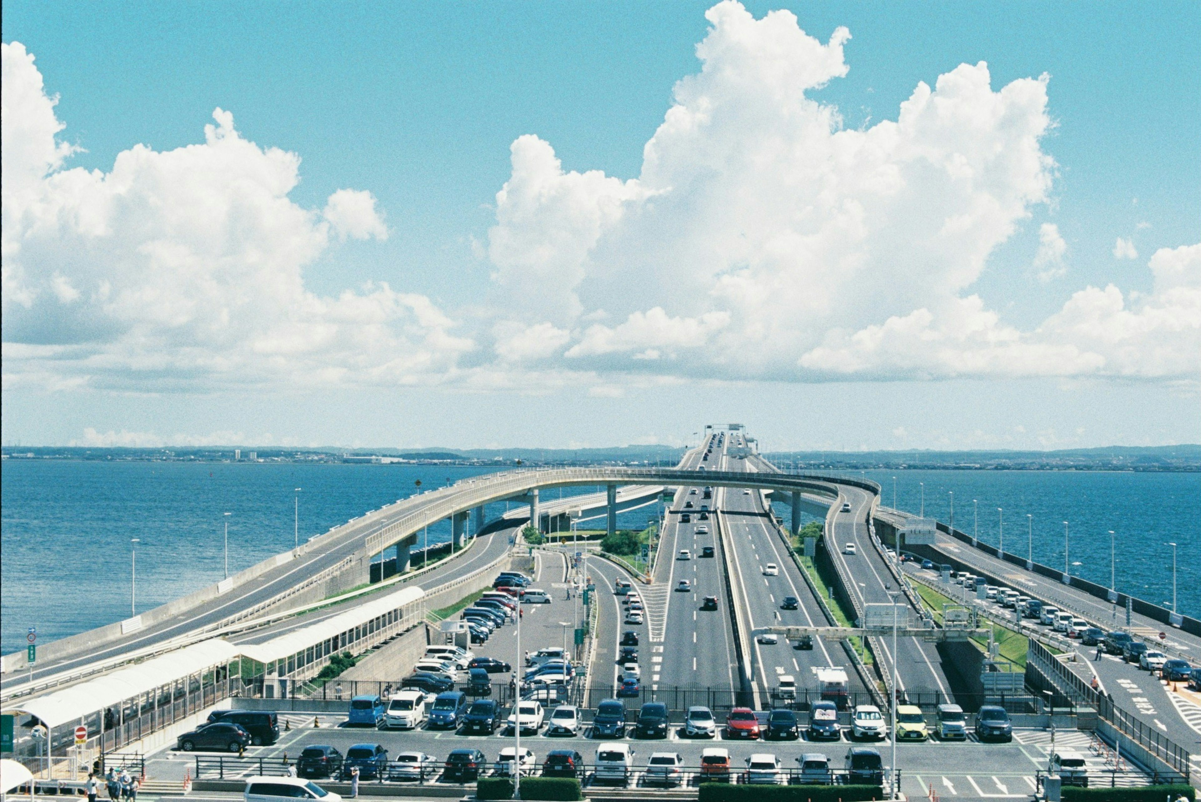 A scenic view of a highway and parking lot under a blue sky with clouds