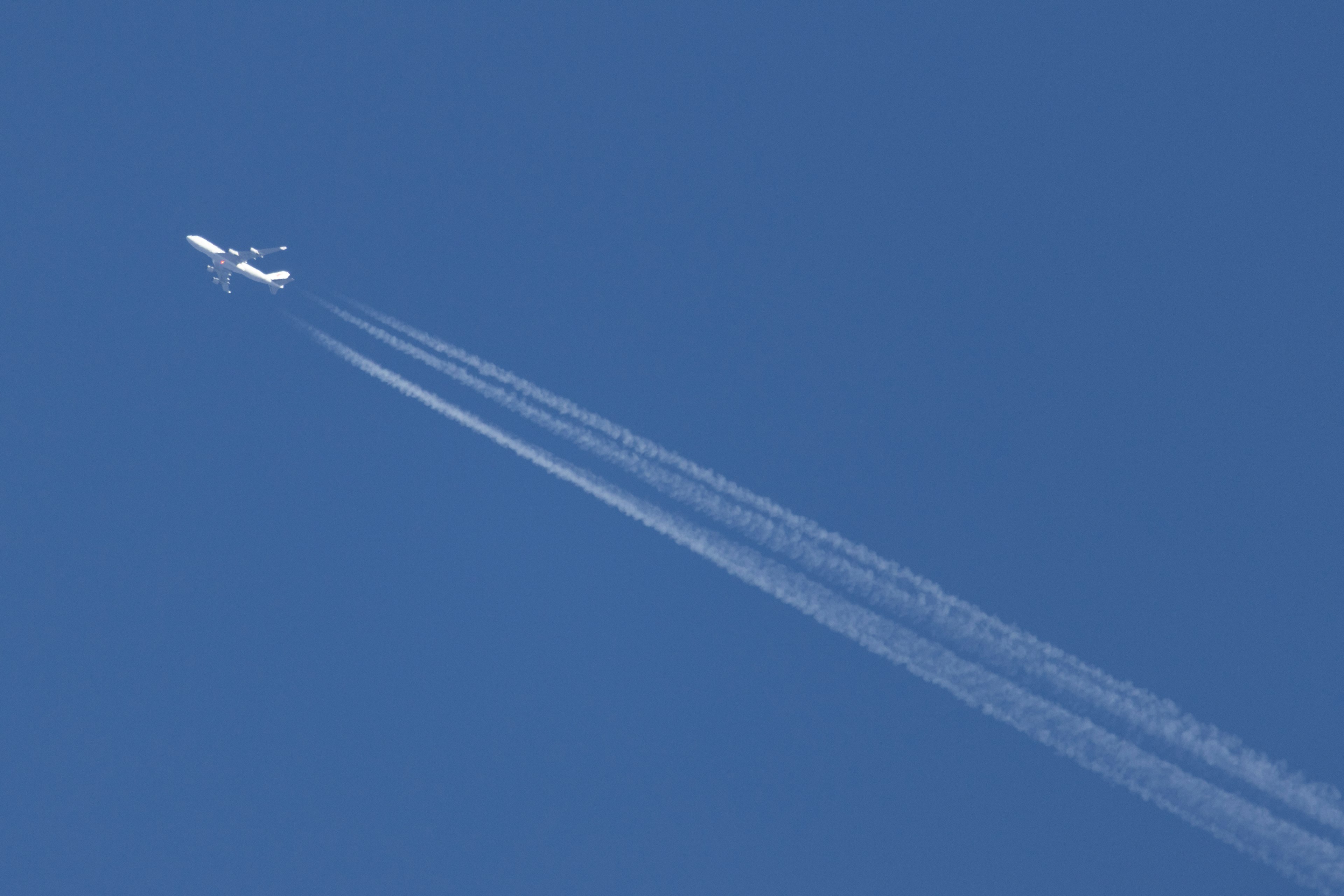 青空に飛ぶ飛行機とその後ろに残る白い飛行機雲