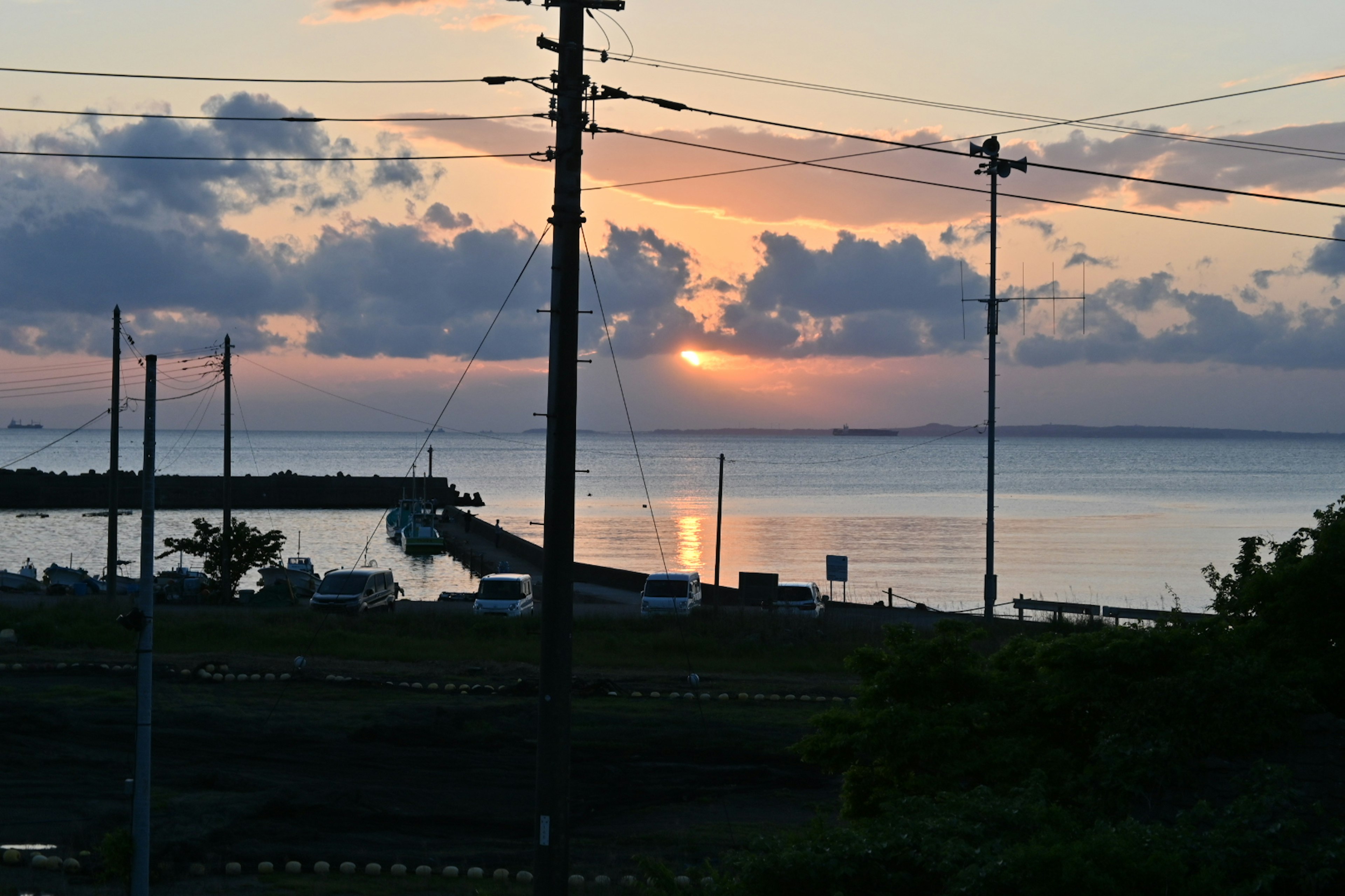 夕日が海に沈む風景と電柱が映る