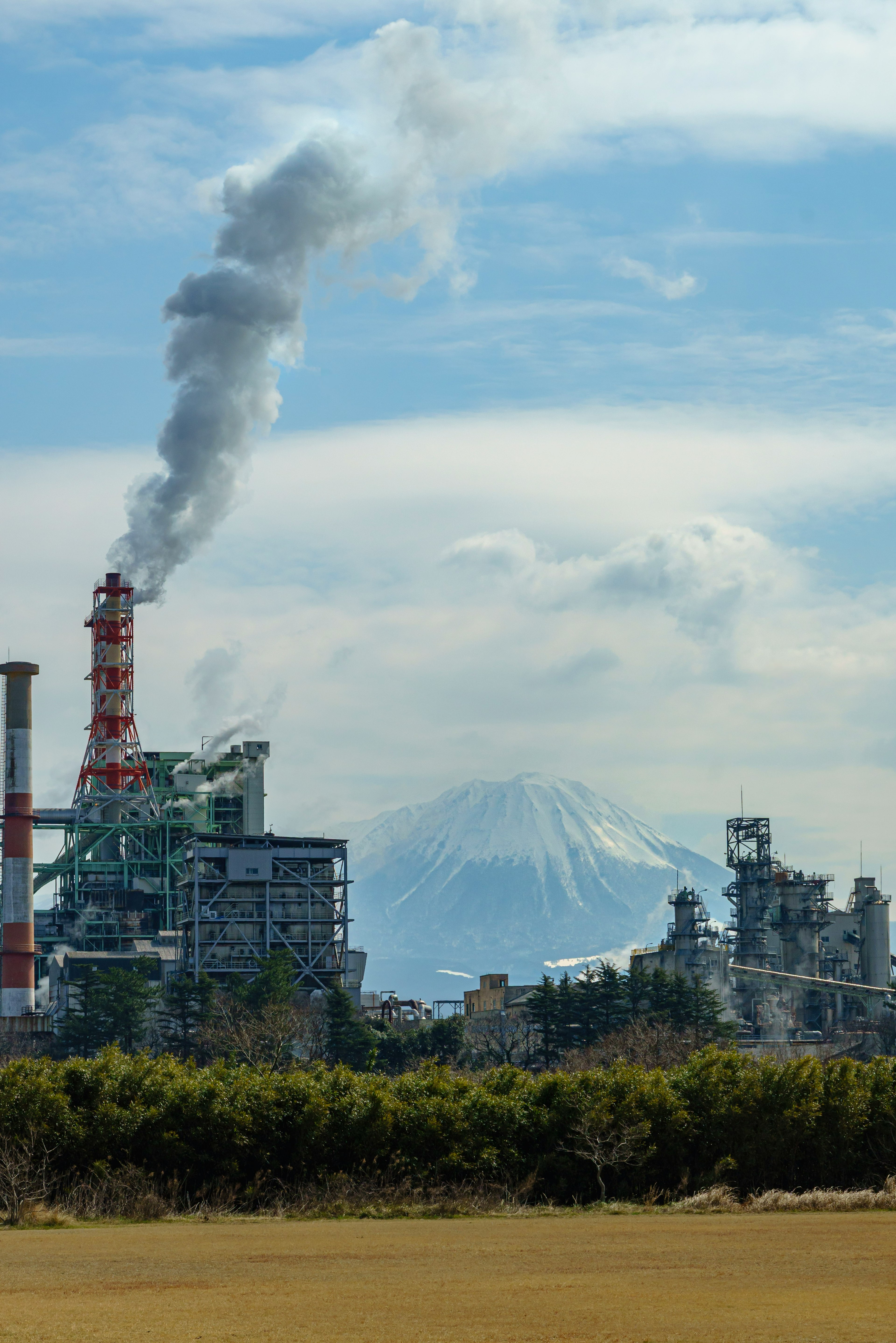 Paesaggio con fabbriche e ciminiere Monte Fuji visibile sullo sfondo