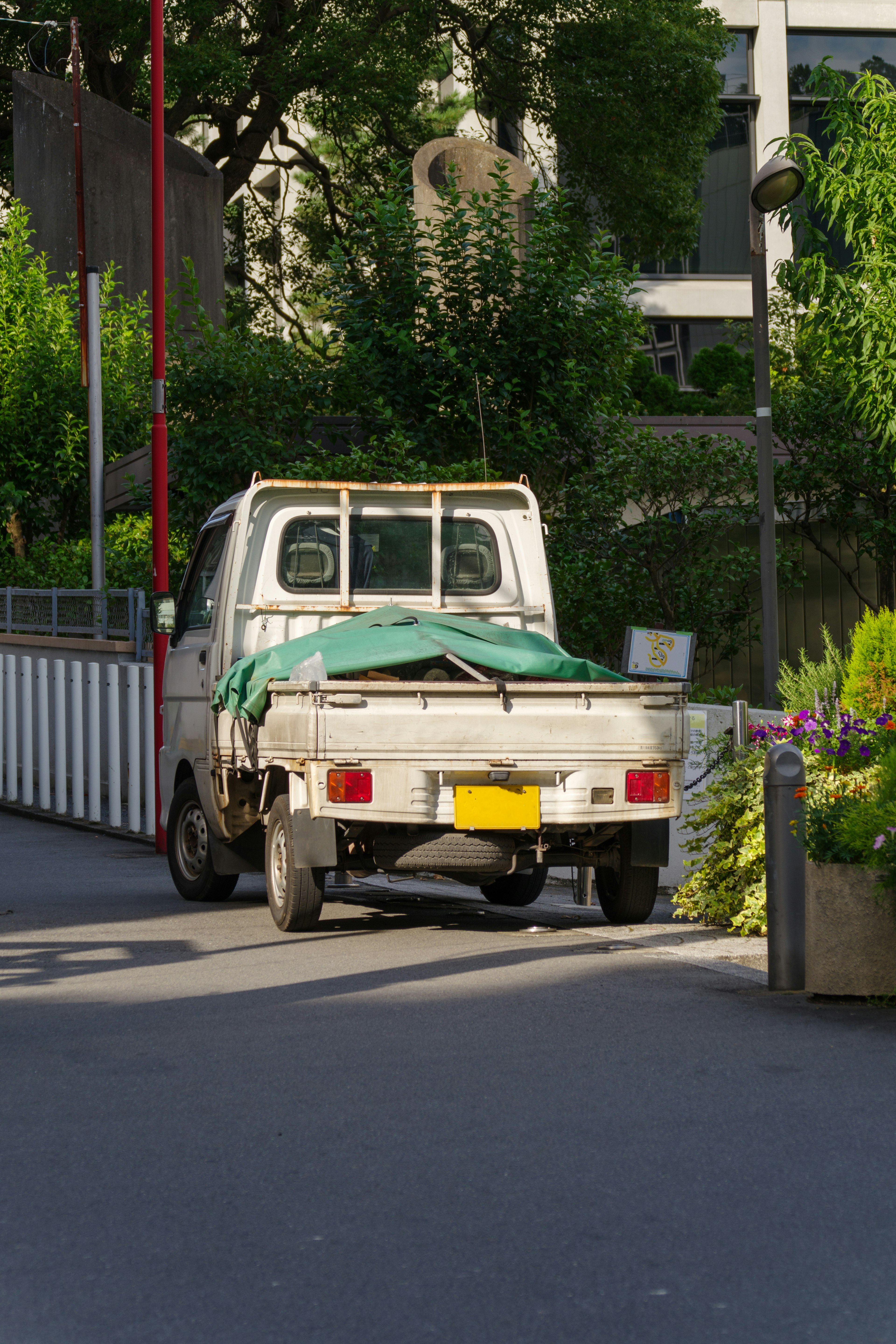 小型貨車帶綠色覆蓋物停在城市街道上