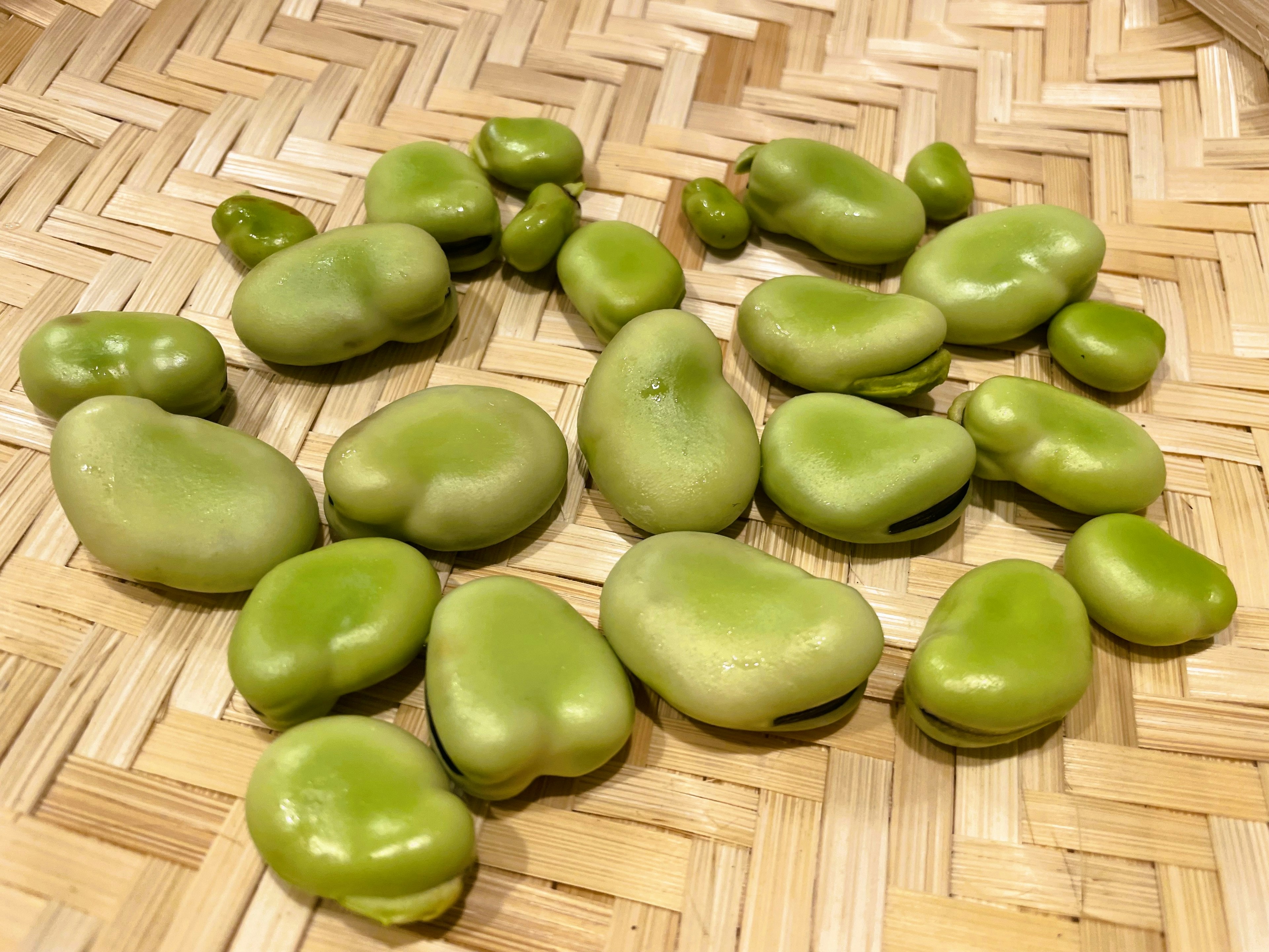 Frijoles fava verdes esparcidos sobre una canasta tejida