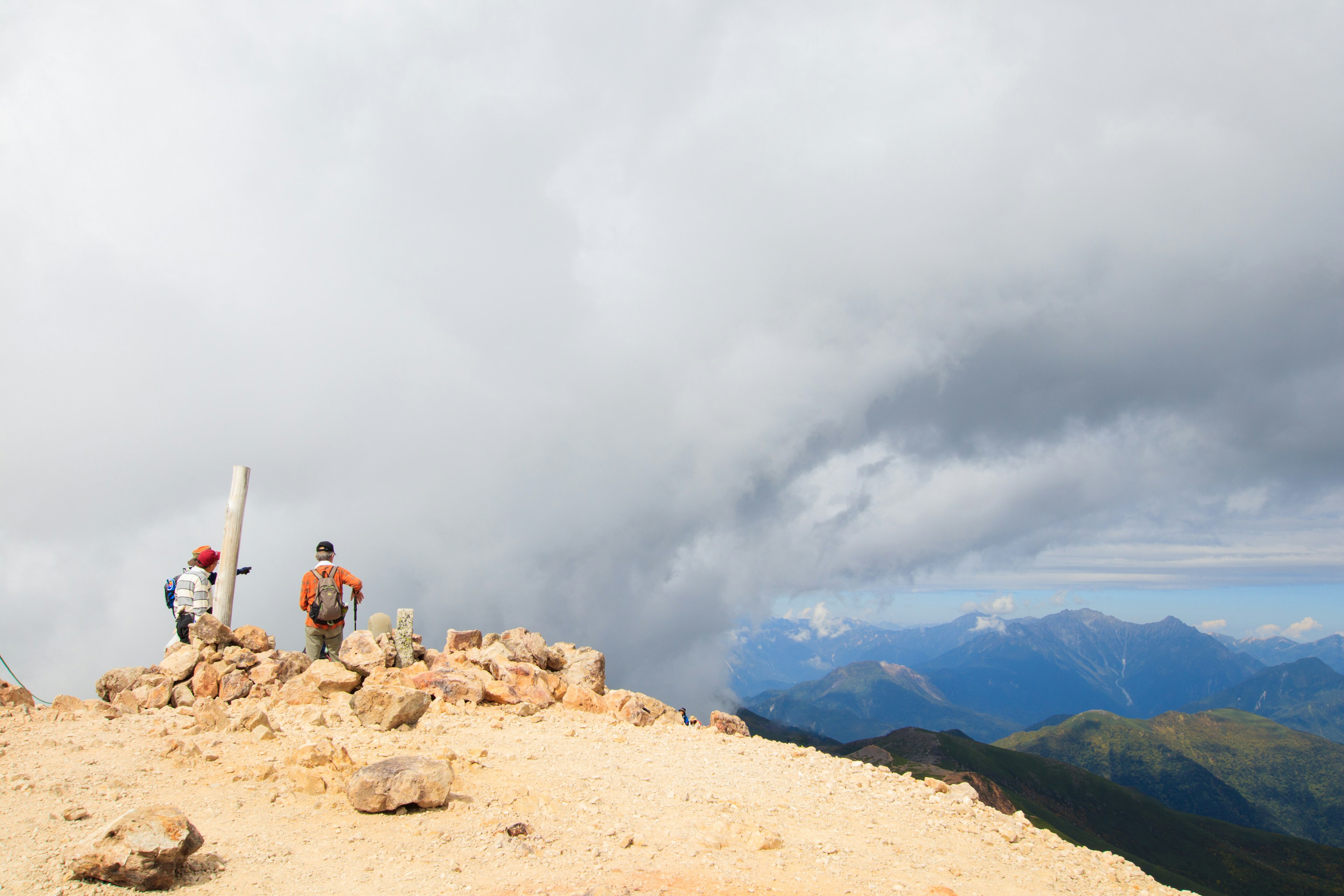 Deux randonneurs debout au sommet d'une montagne avec un ciel nuageux