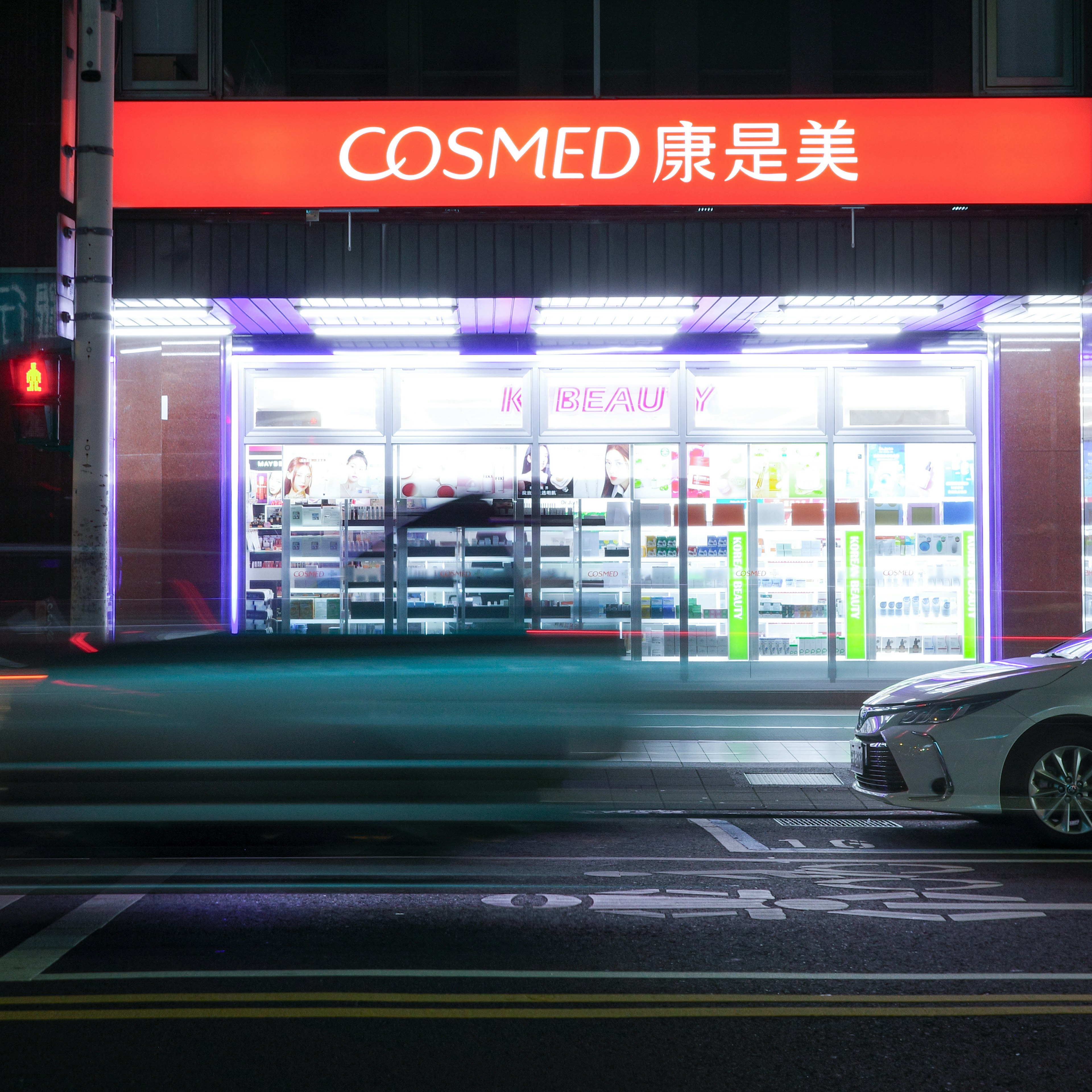 COSMED store illuminated at night along the street