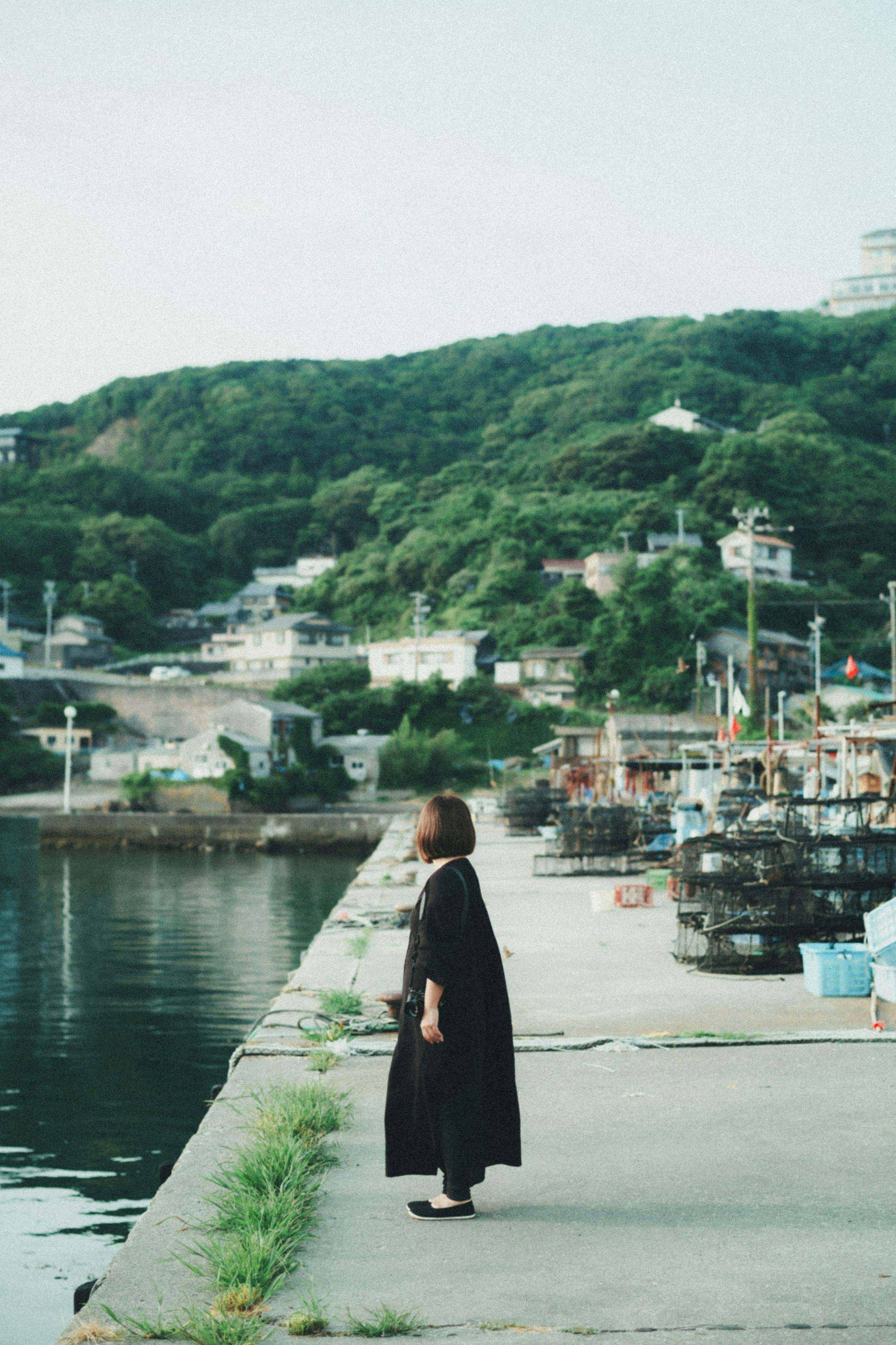 海岸に立つ女性と緑の山々の風景