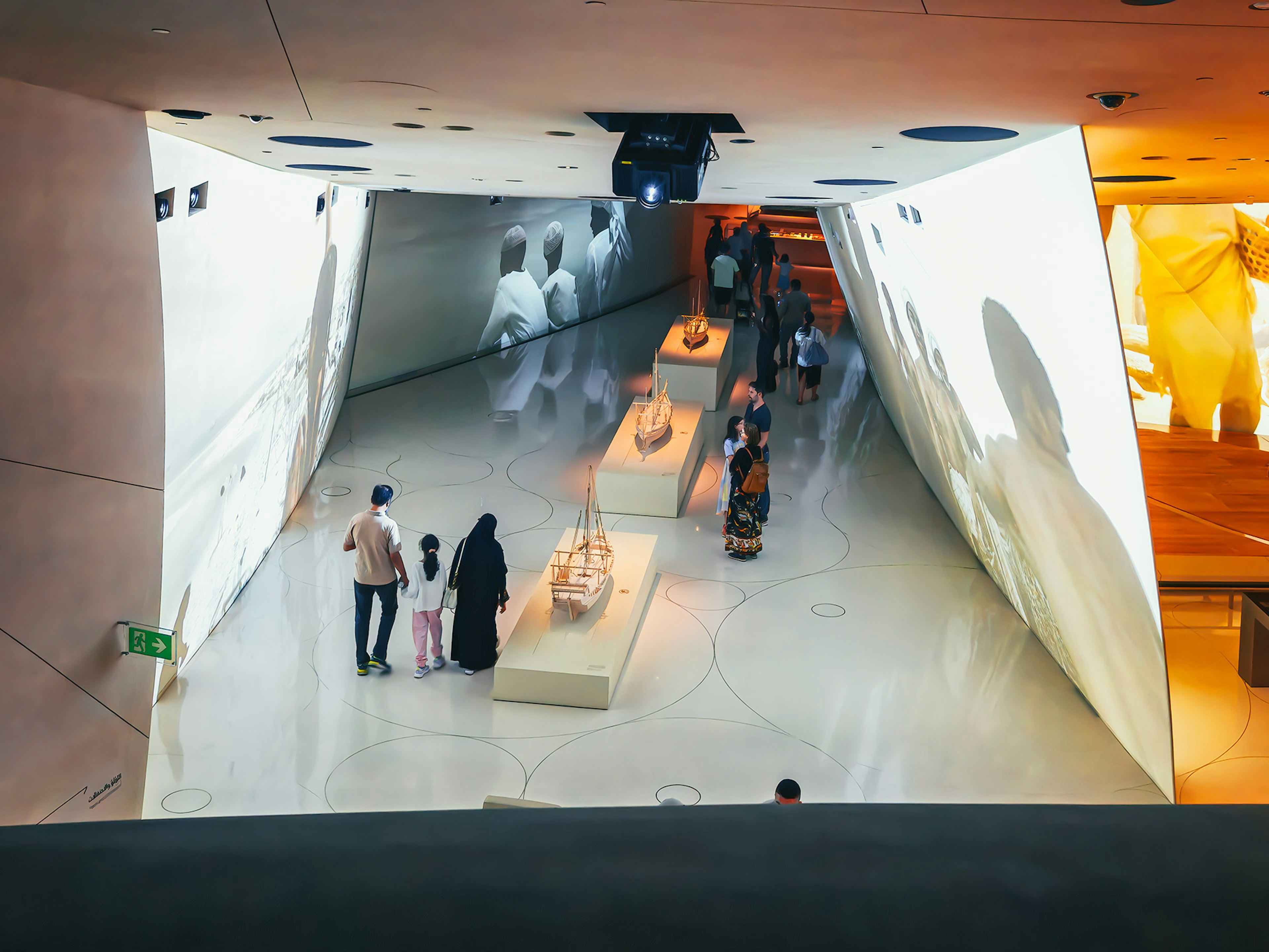 現代的な博物館の内部で展示品を見ている家族の姿と映像プロジェクション