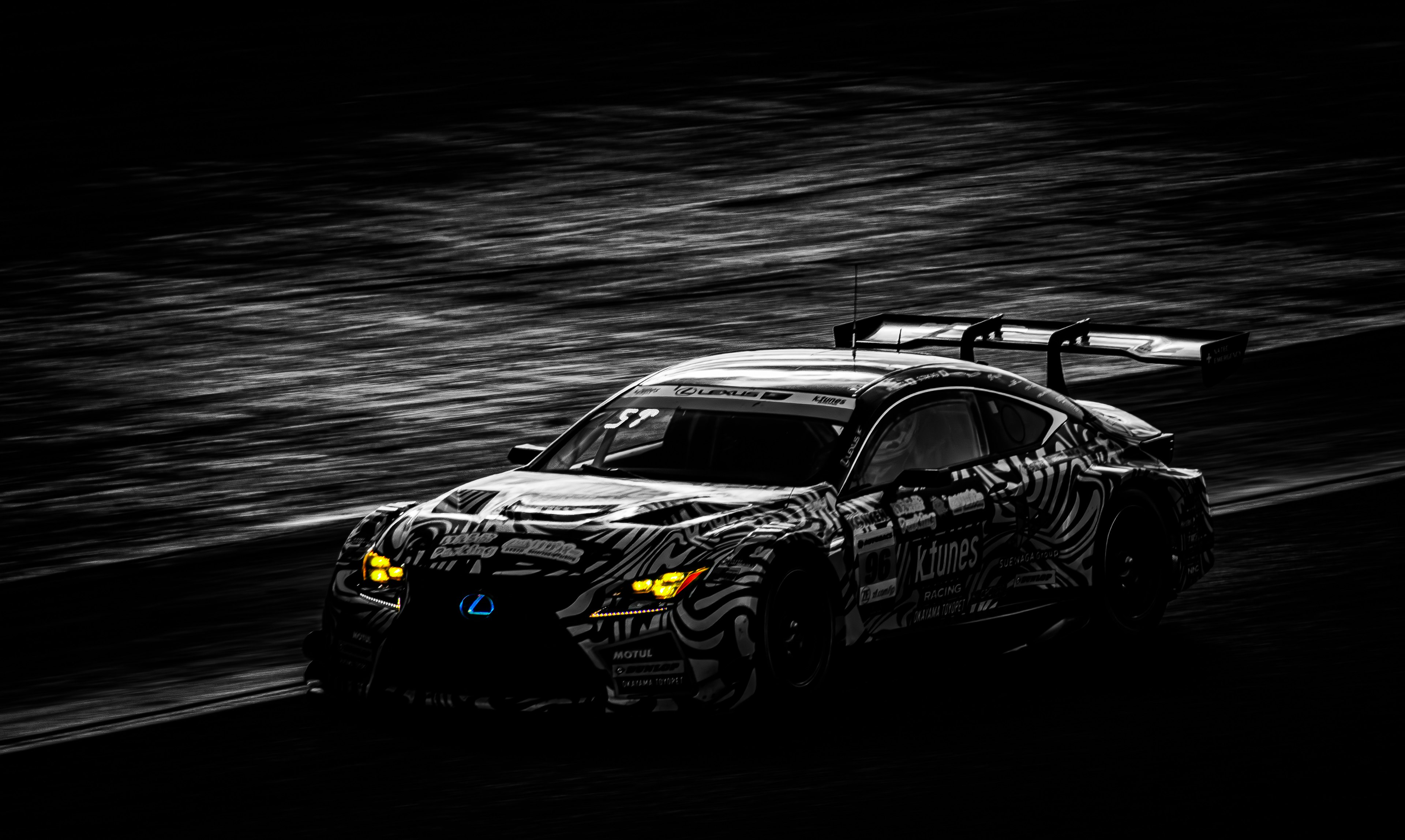 Sporty black racing car speeding through a dark background