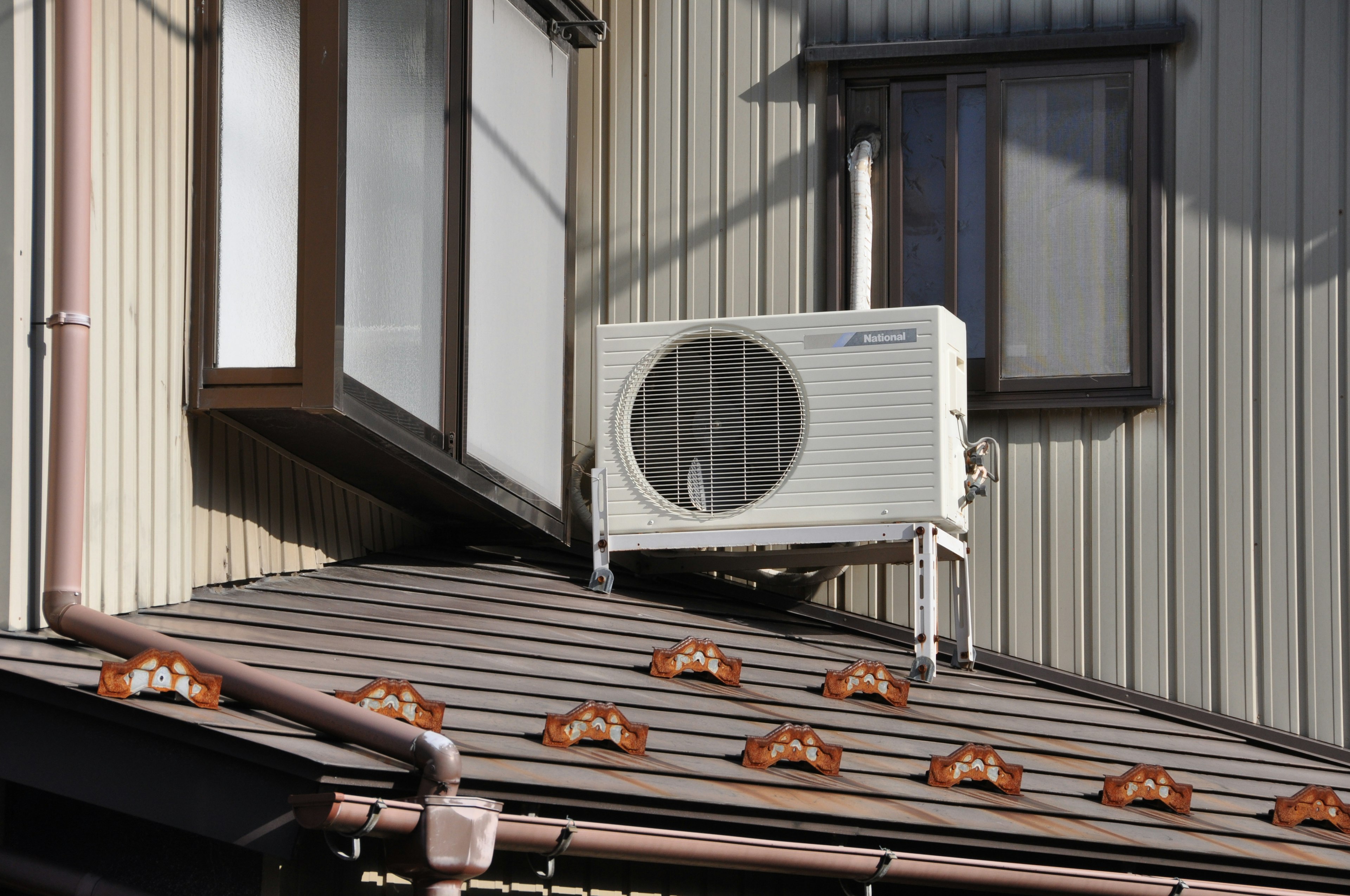 Air conditioning unit installed on the roof of a house with windows