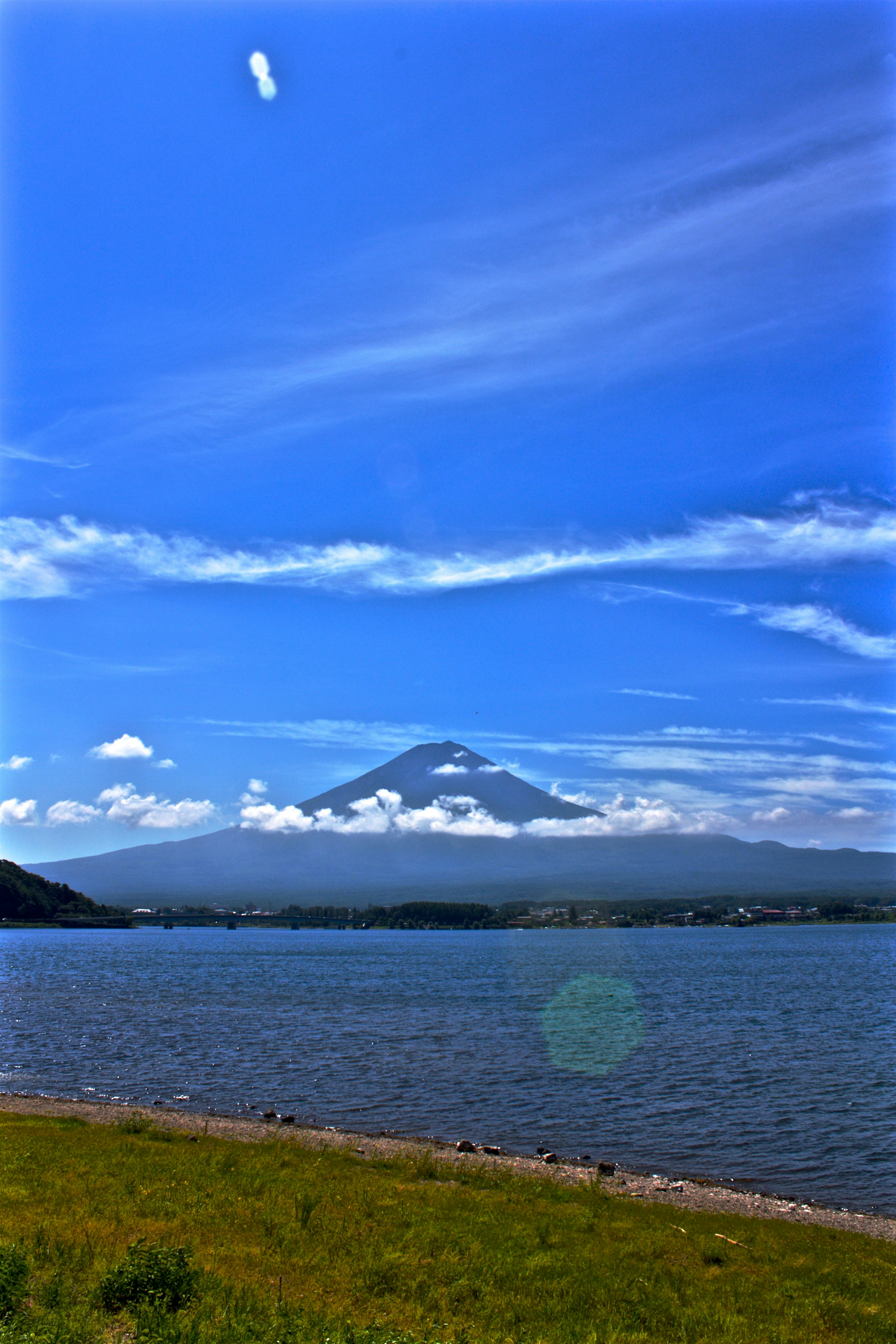 Vista panoramica del monte Fuji sotto un cielo blu chiaro con un lago