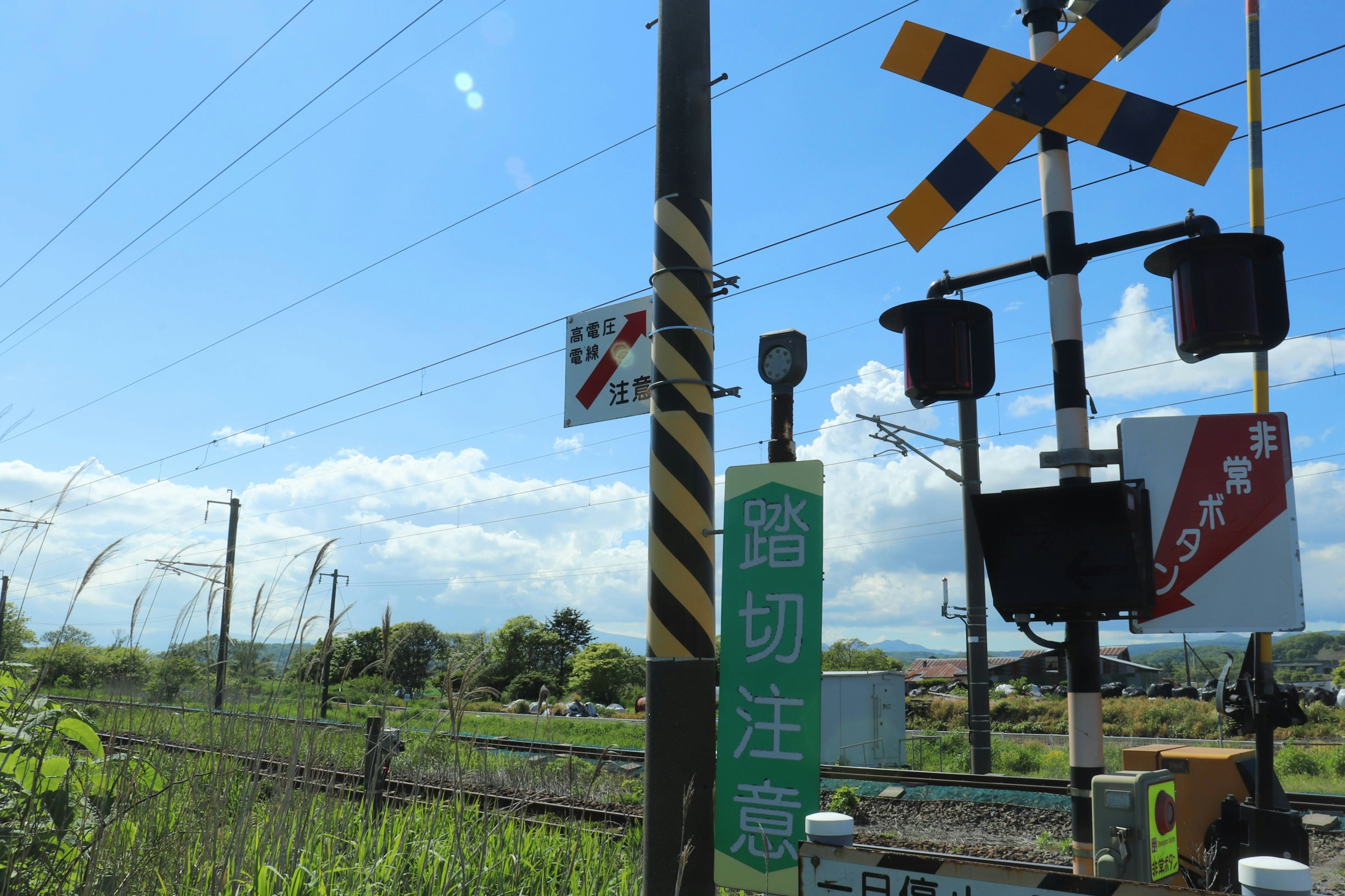 Railroad crossing sign and warning lights under a blue sky