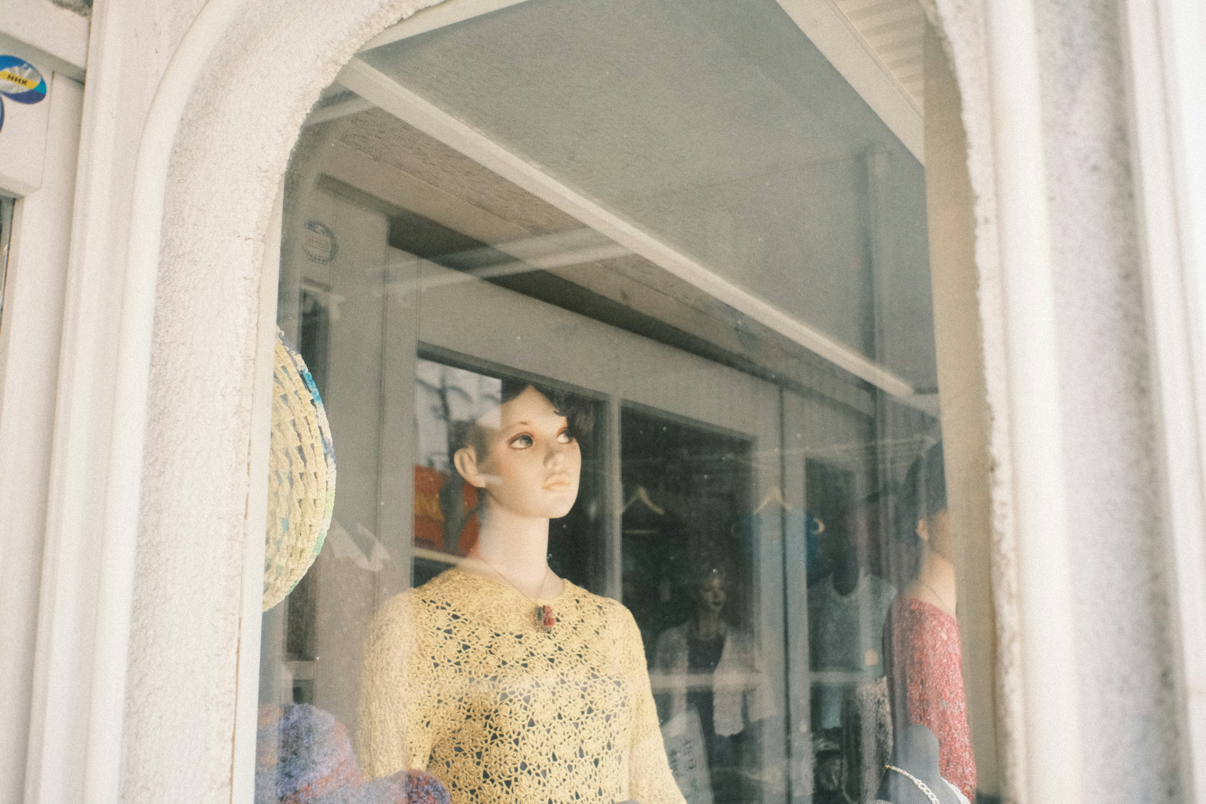 Mannequin in a window display wearing a yellow dress