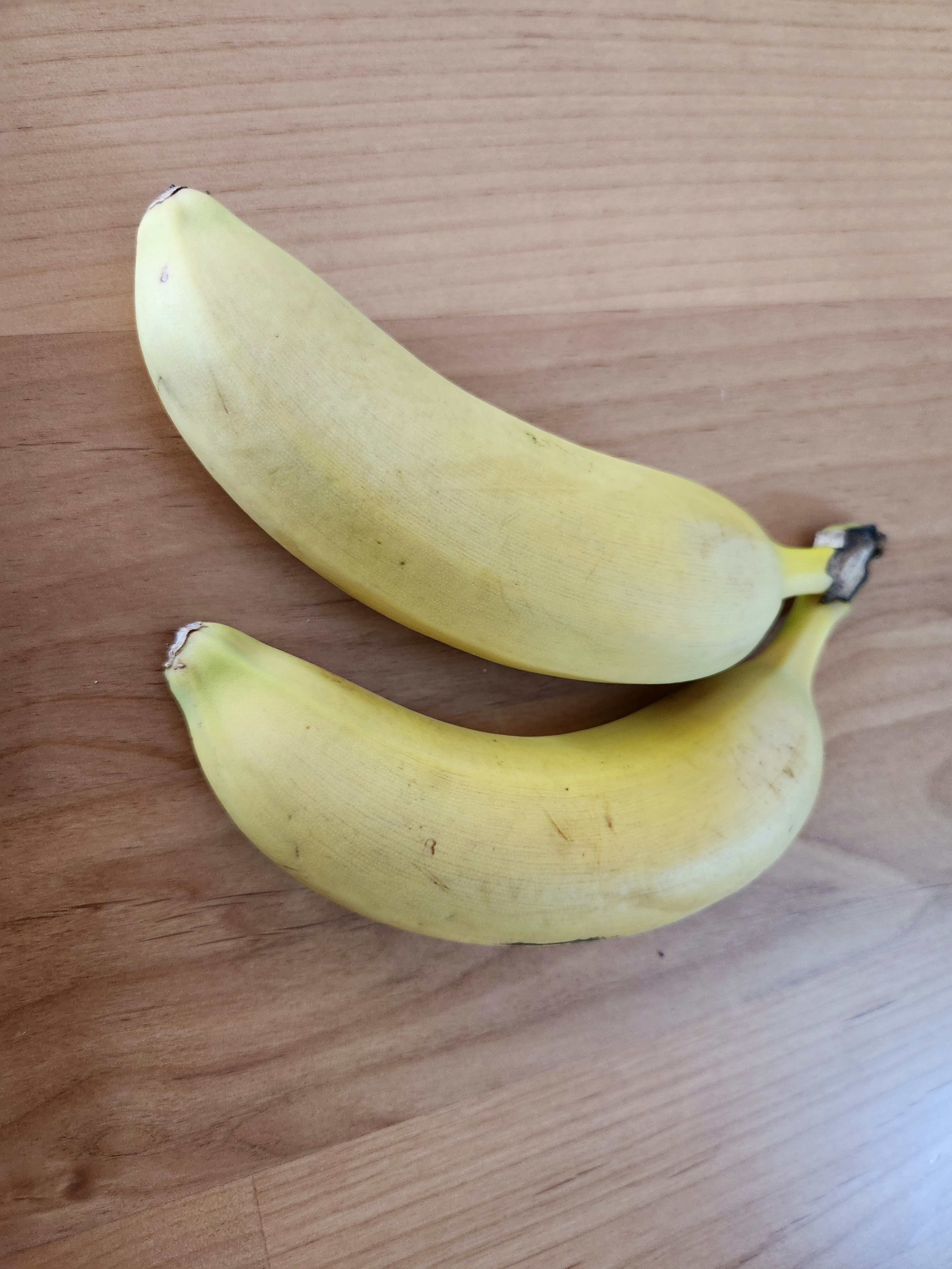 Dua pisang kuning di atas meja kayu