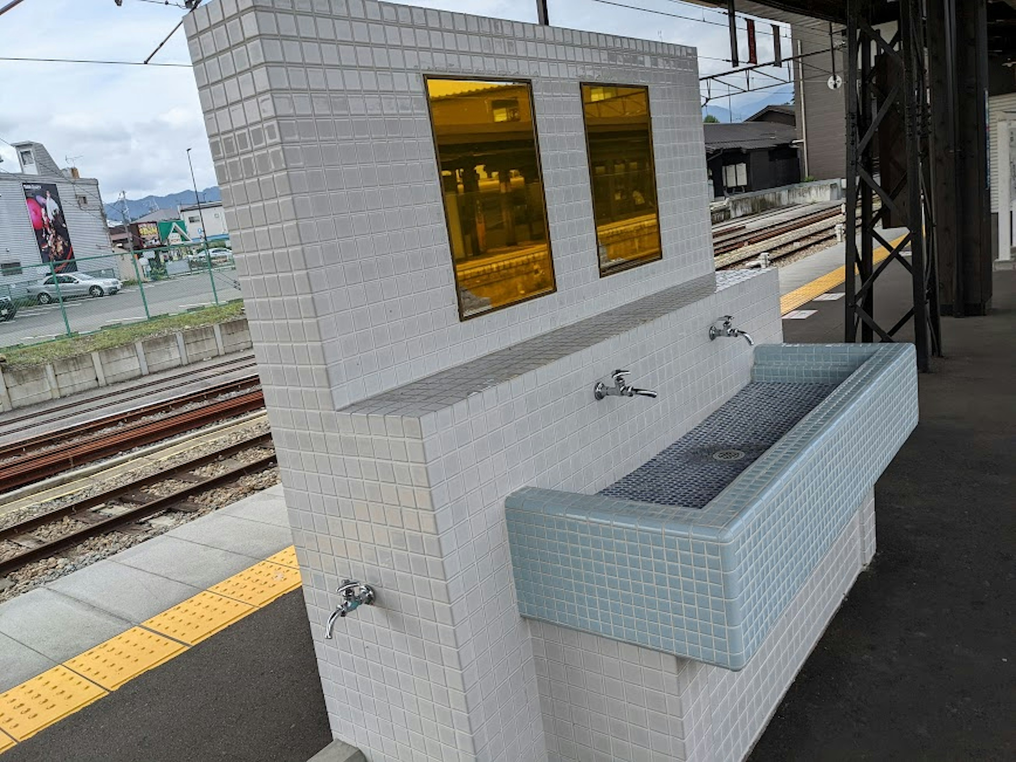 White tiled sink with golden windows at a train station