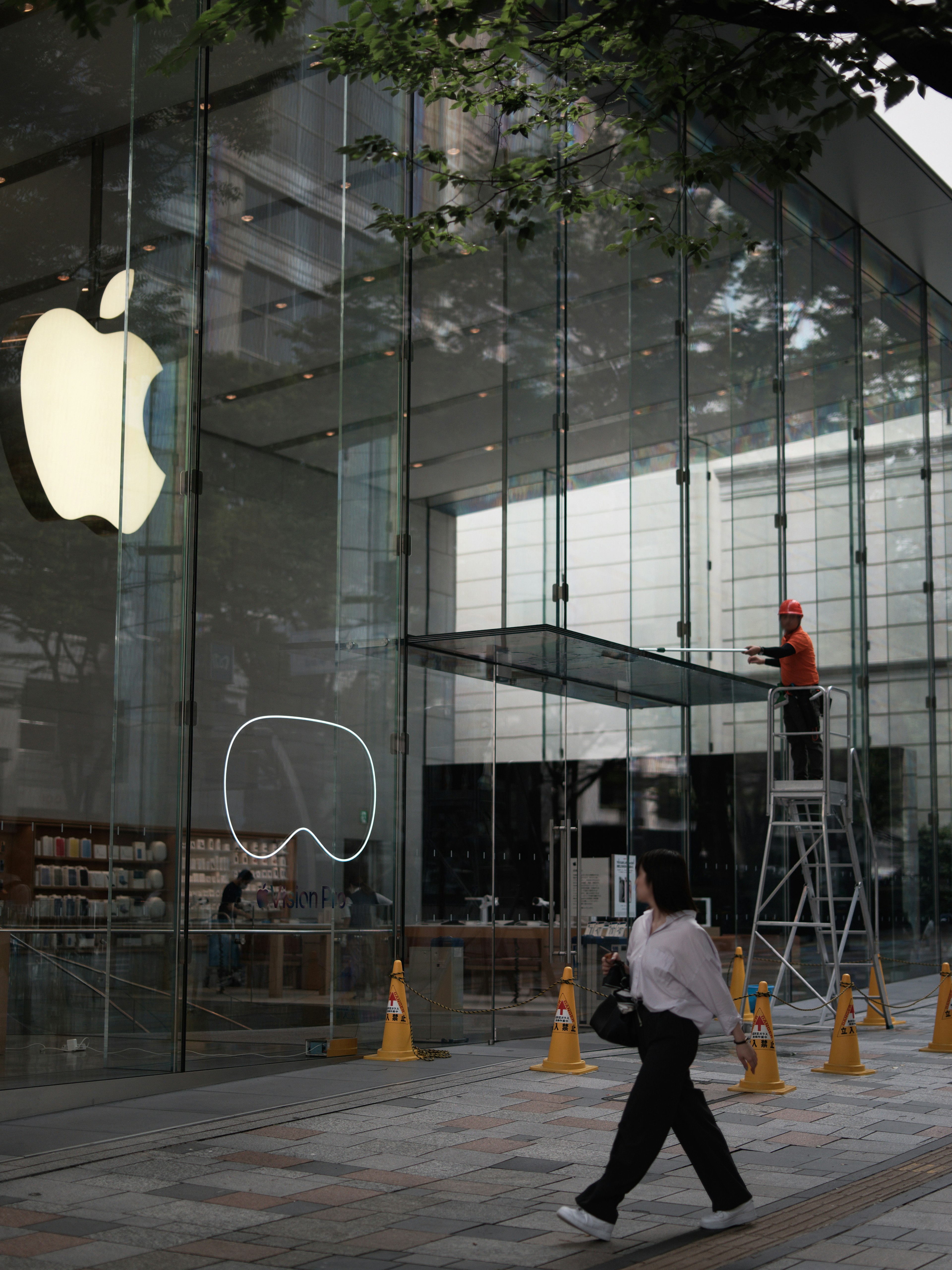 Extérieur d'un Apple Store en verre avec un travailleur sur une échelle