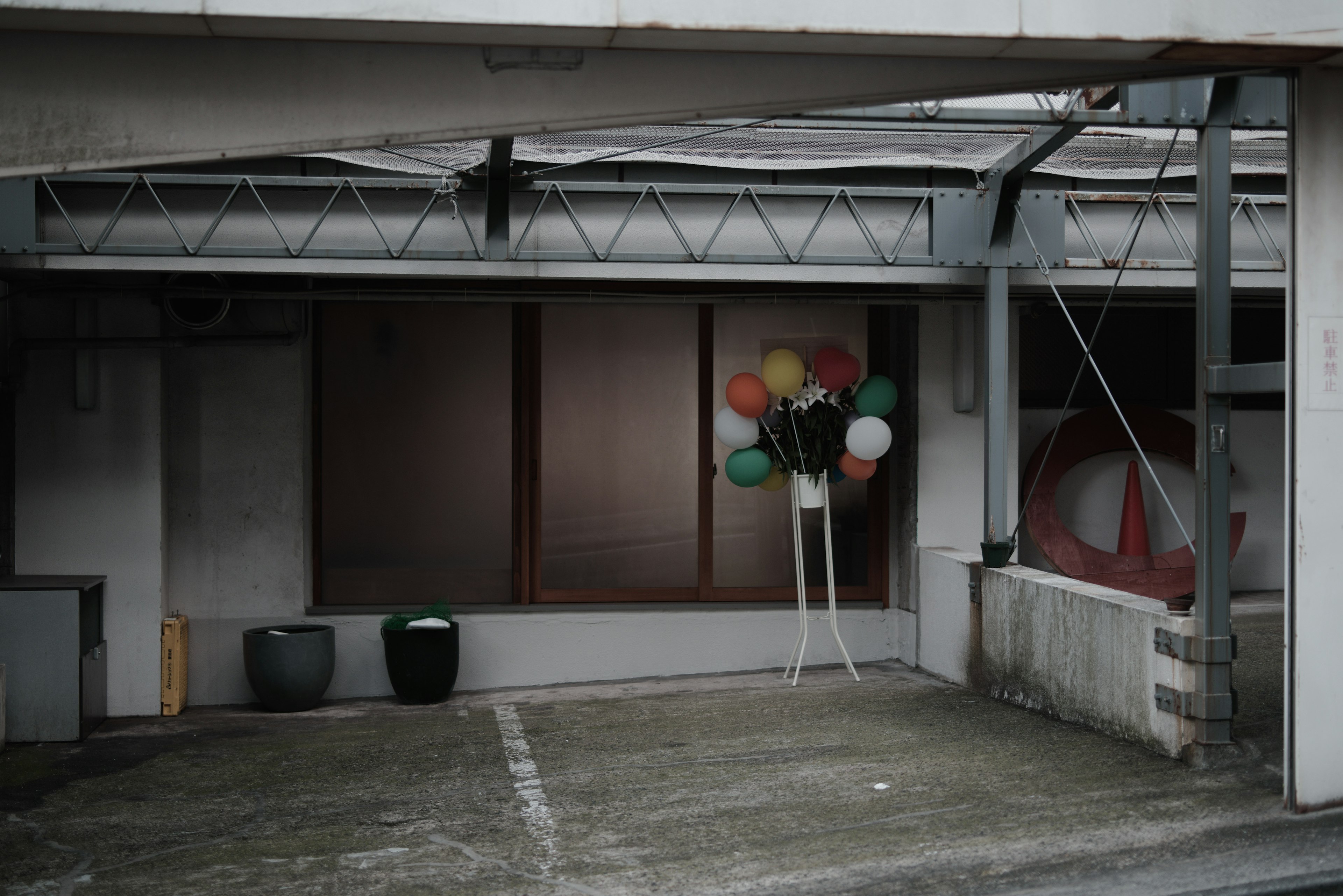 A secluded area with colorful balloons against a gray wall