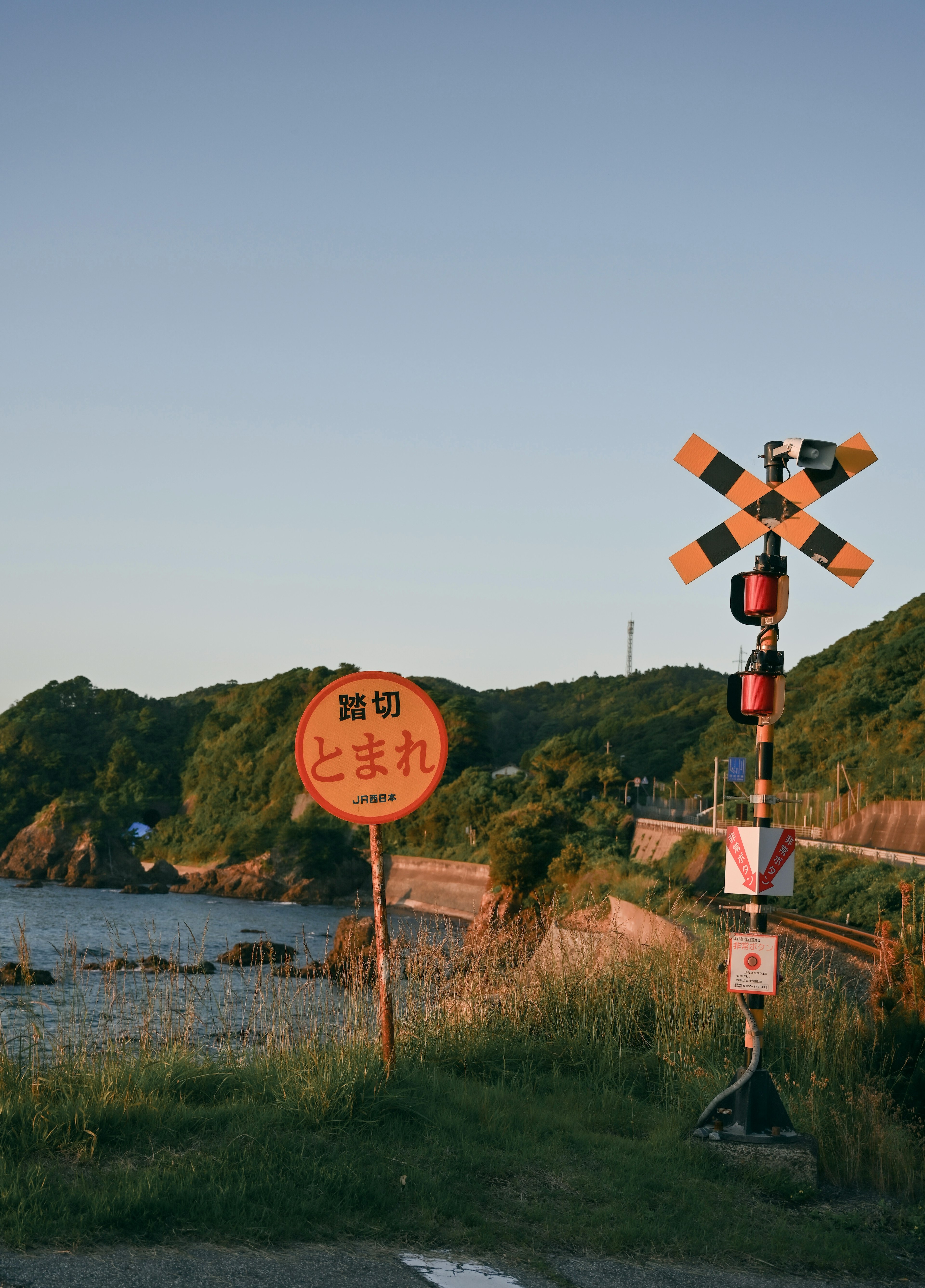 Scenic view of a railroad crossing and sign near the sea