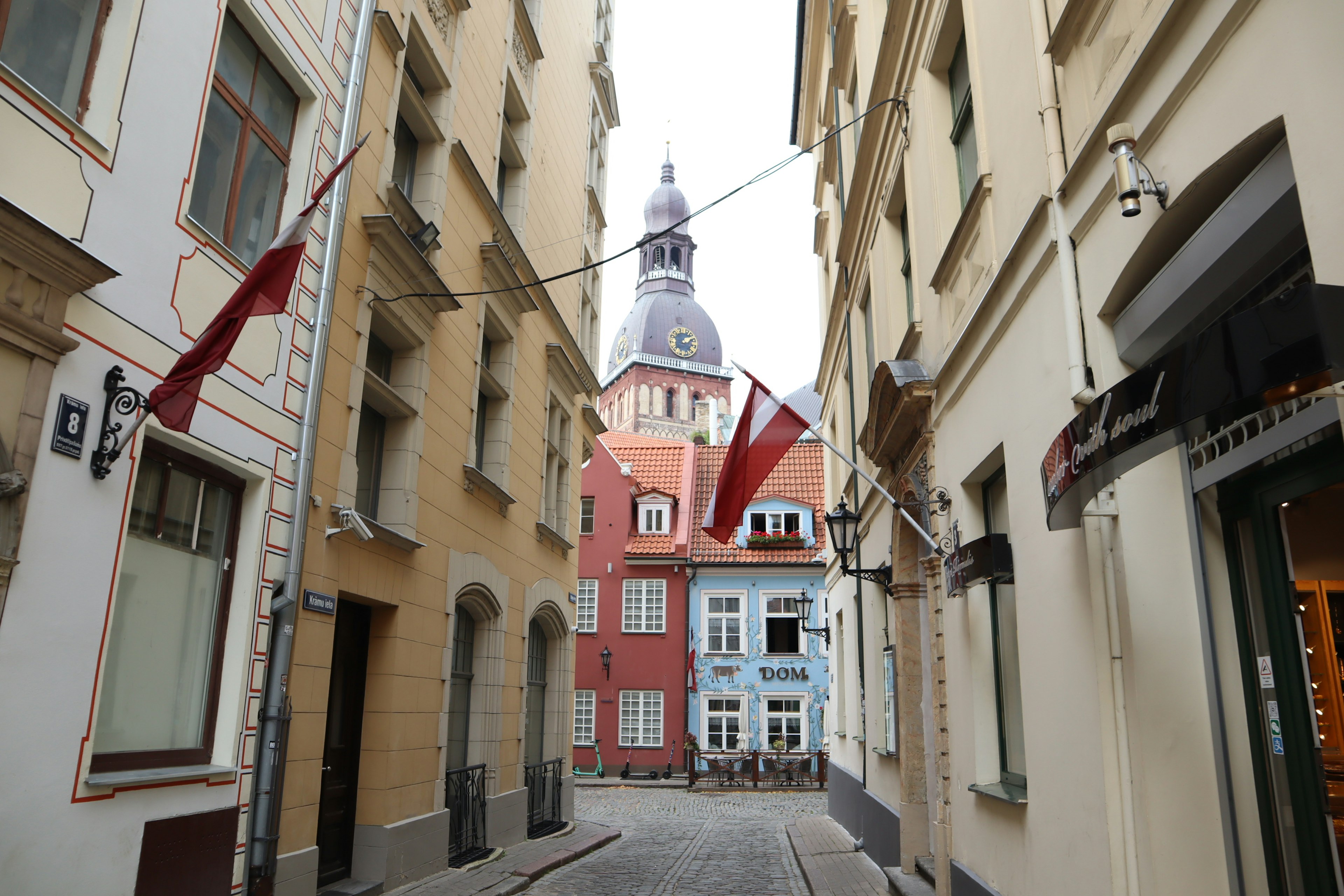 Narrow street in Riga Latvia featuring colorful buildings and flags