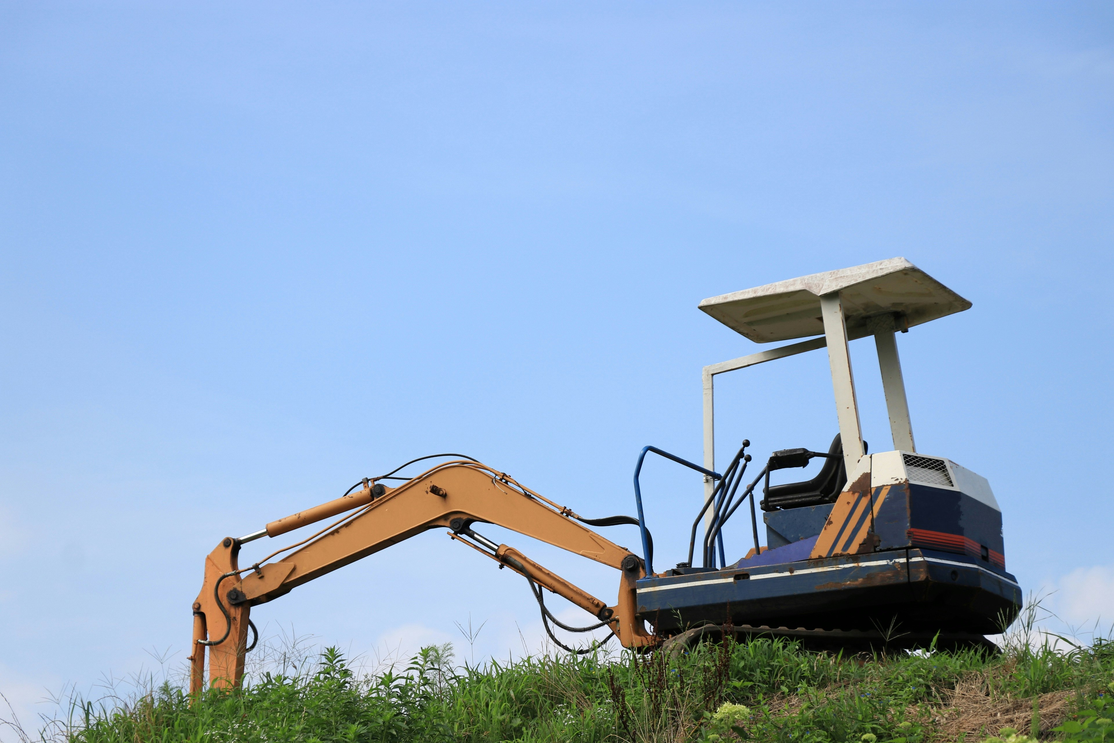 Yellow excavator on green grass under blue sky