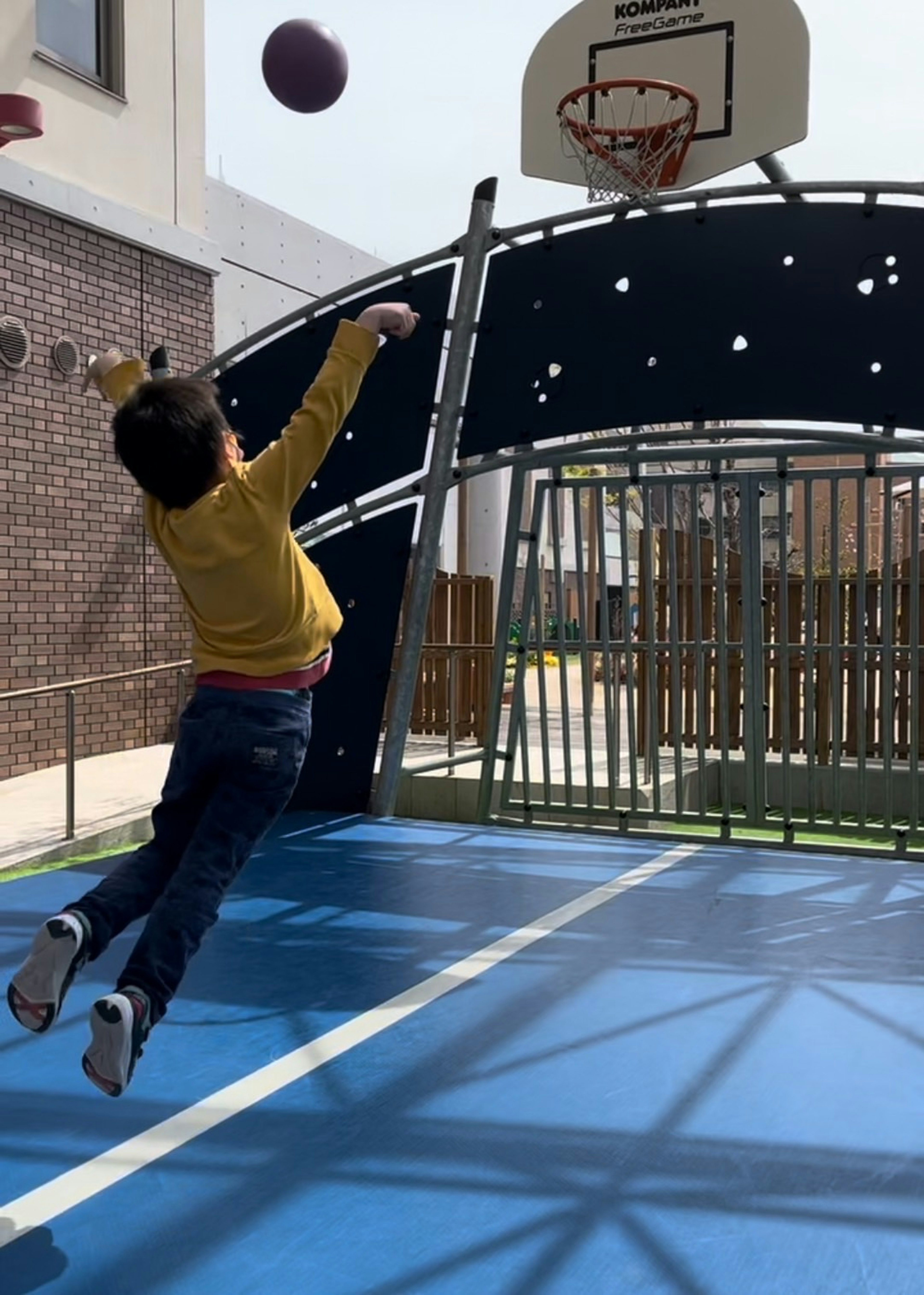 Niño saltando para lanzar una pelota de baloncesto en un parque infantil