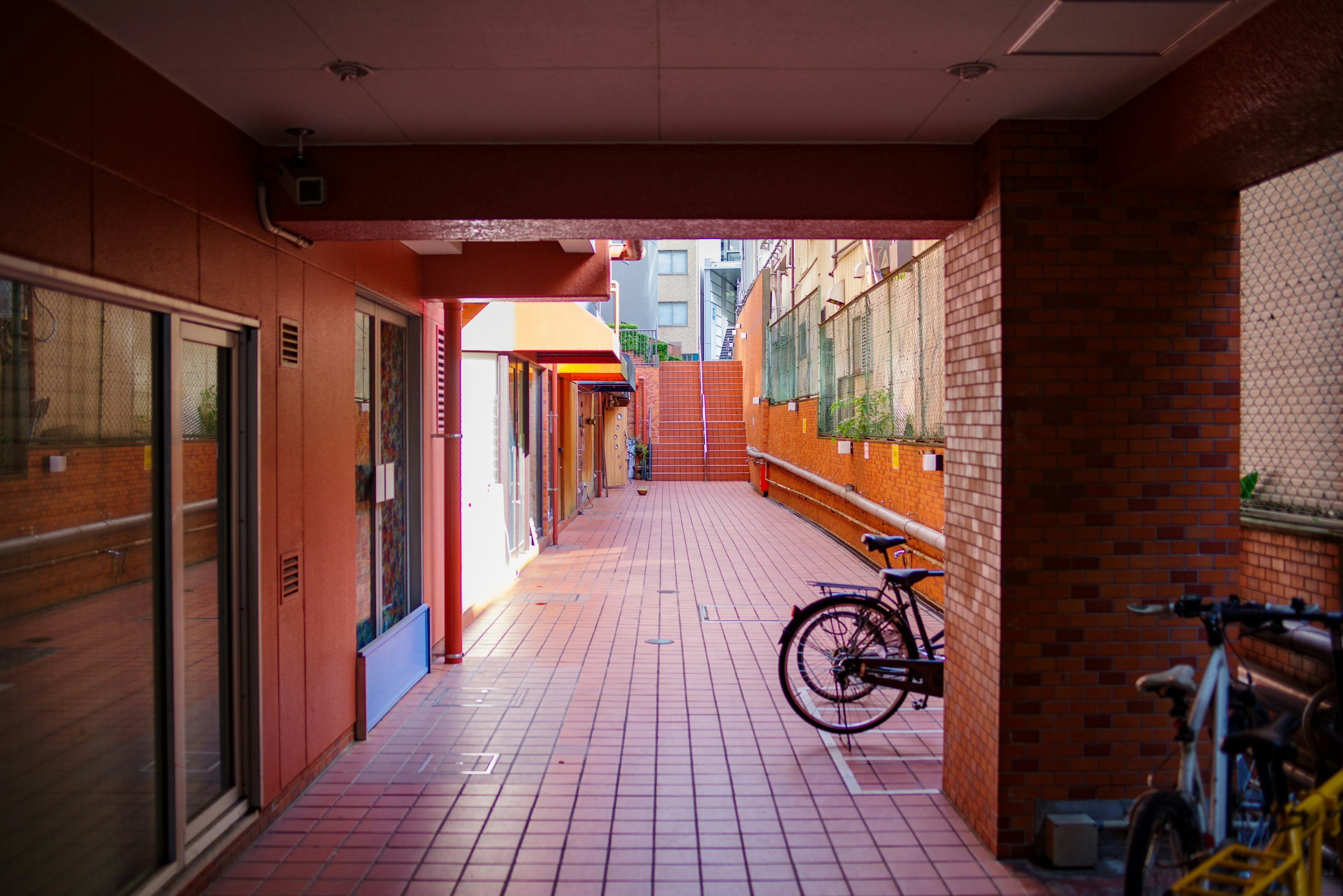 A corridor with red walls and tiles featuring parked bicycles