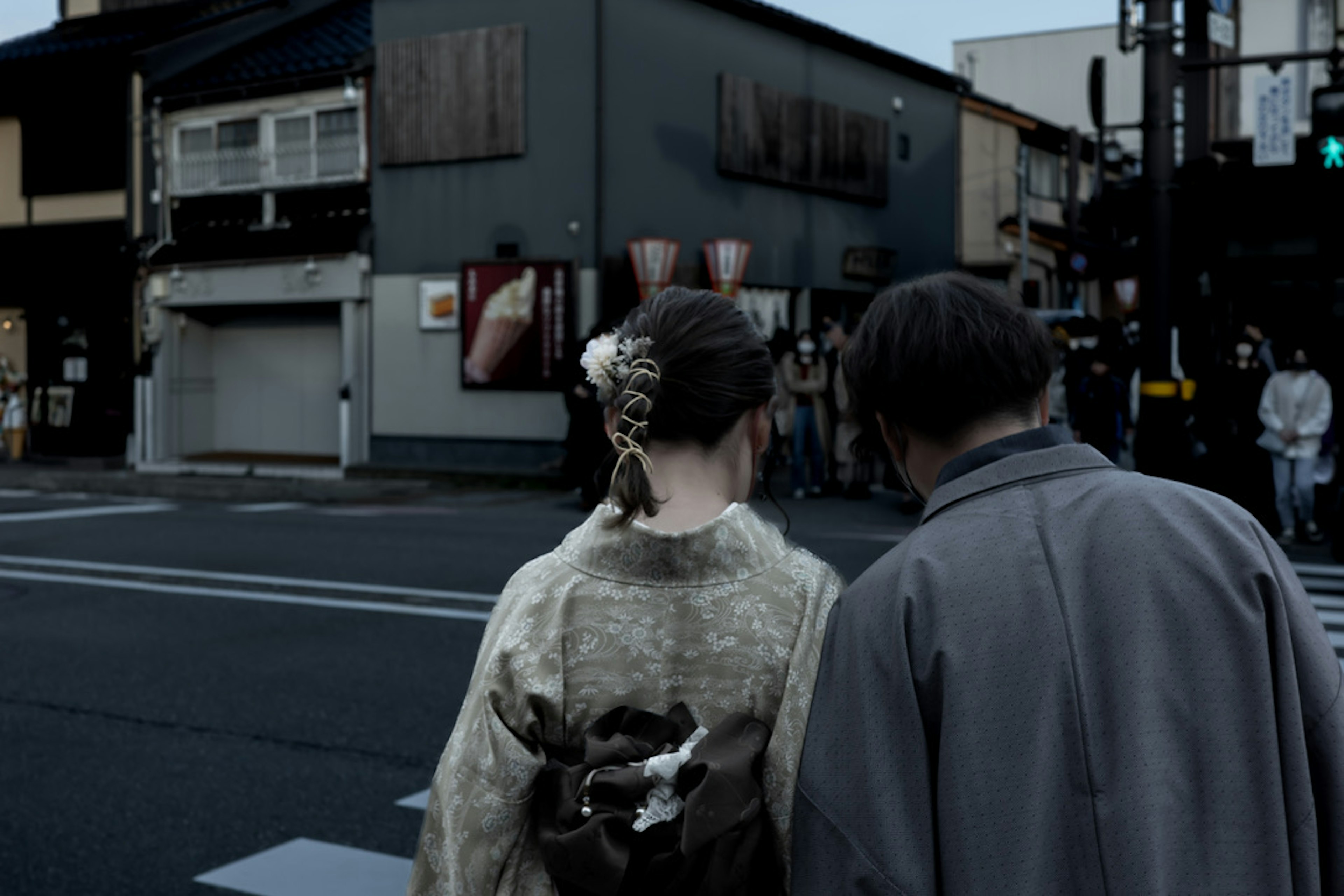 Rückansicht einer Frau im Kimono und eines Mannes, die nachts durch die Stadt gehen