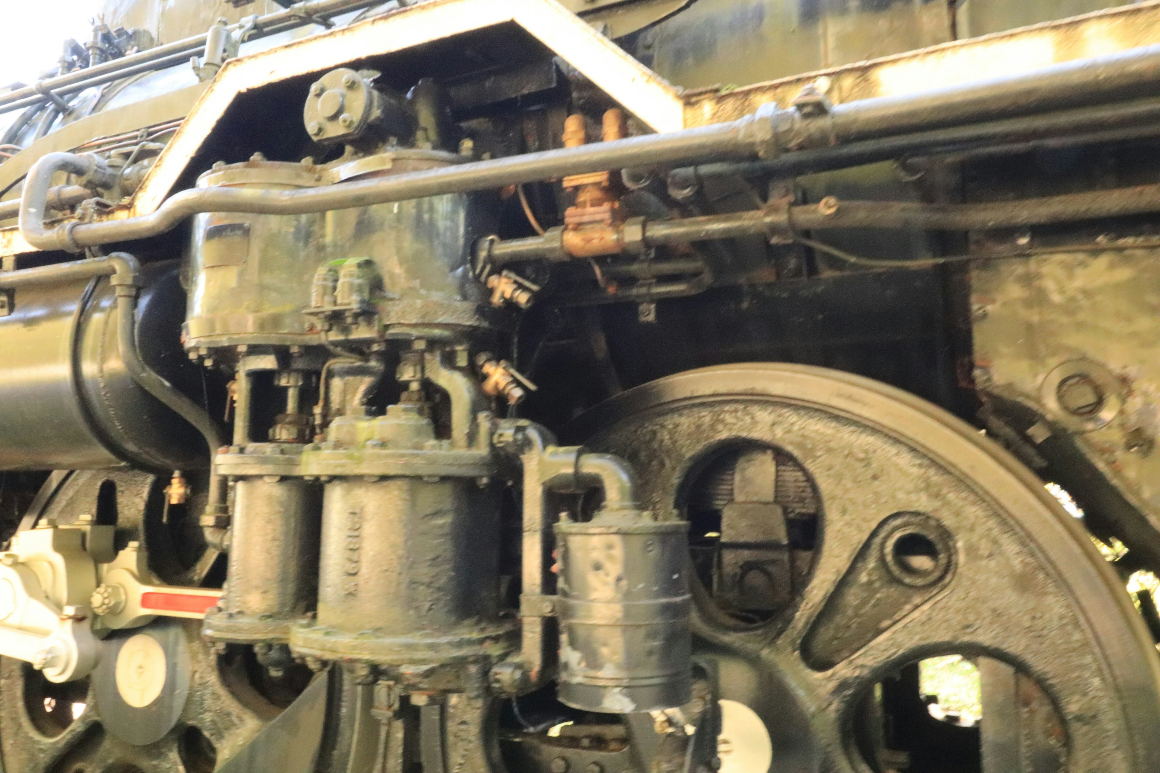 Image en gros plan d'un moteur de locomotive à vapeur montrant des pièces métalliques rouillées et une grande roue