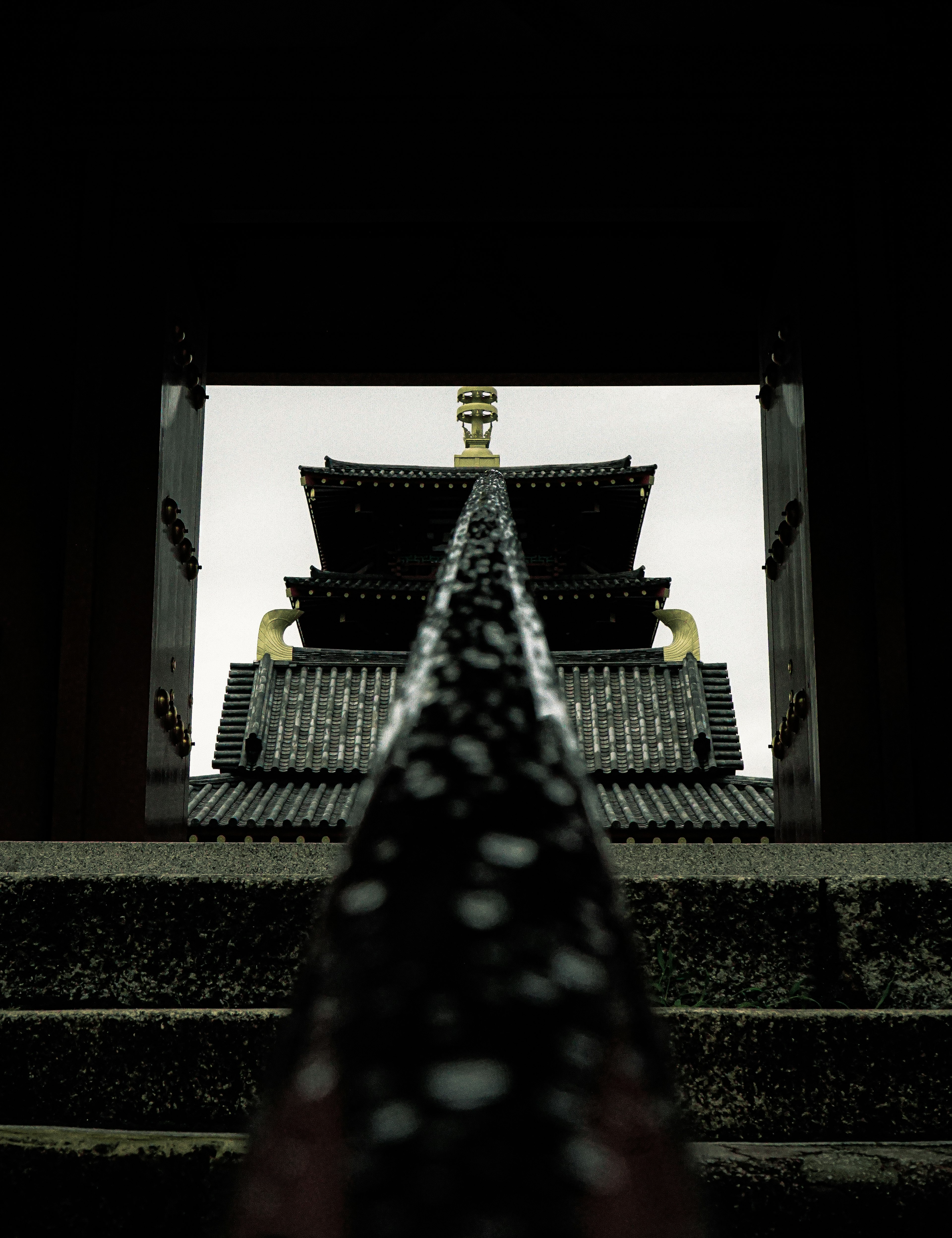 階段から見上げる寺院の塔の視点、暗い背景に金色の装飾