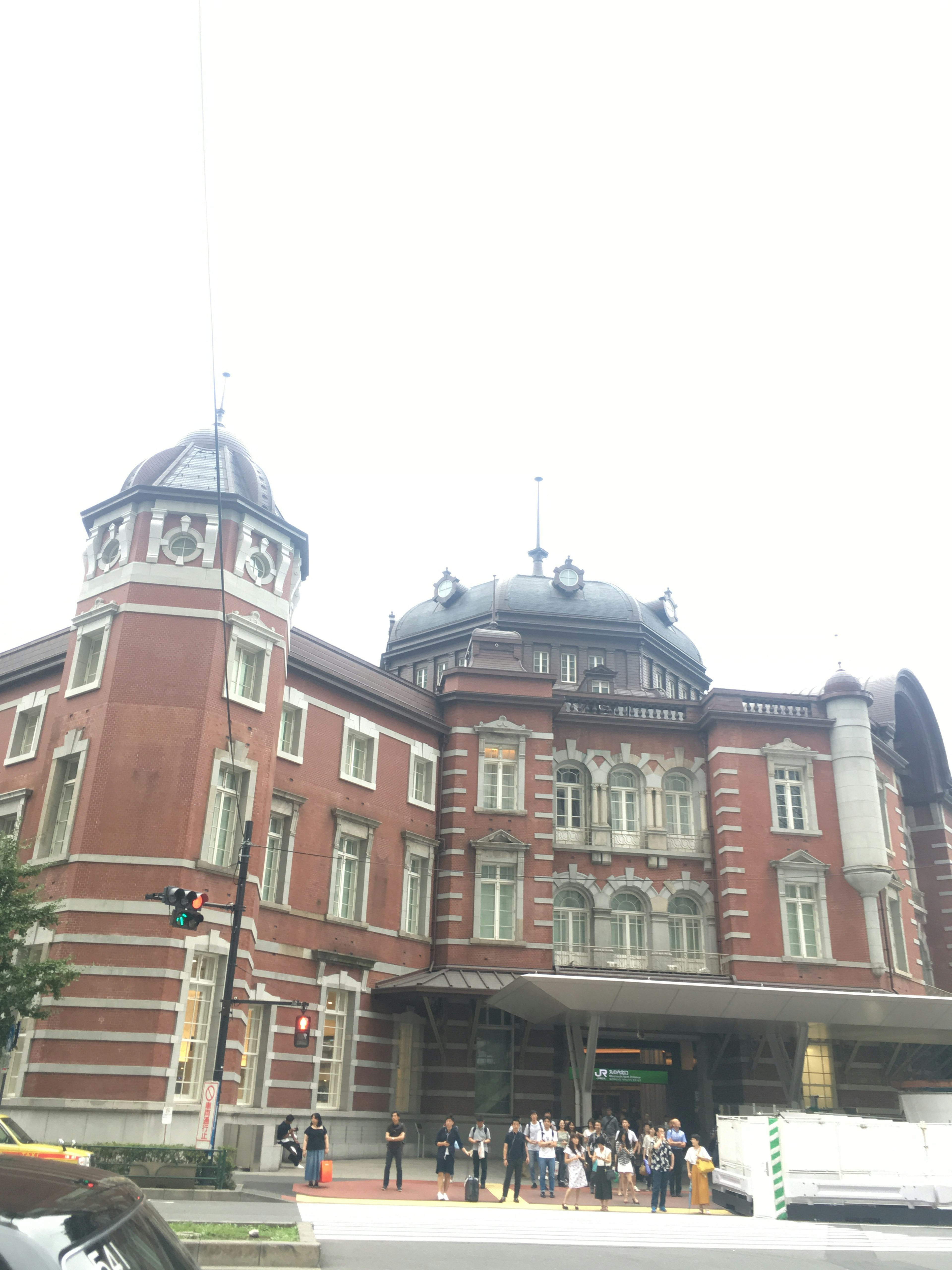 Exterior view of Tokyo Station featuring red brick walls and dome-shaped roofs