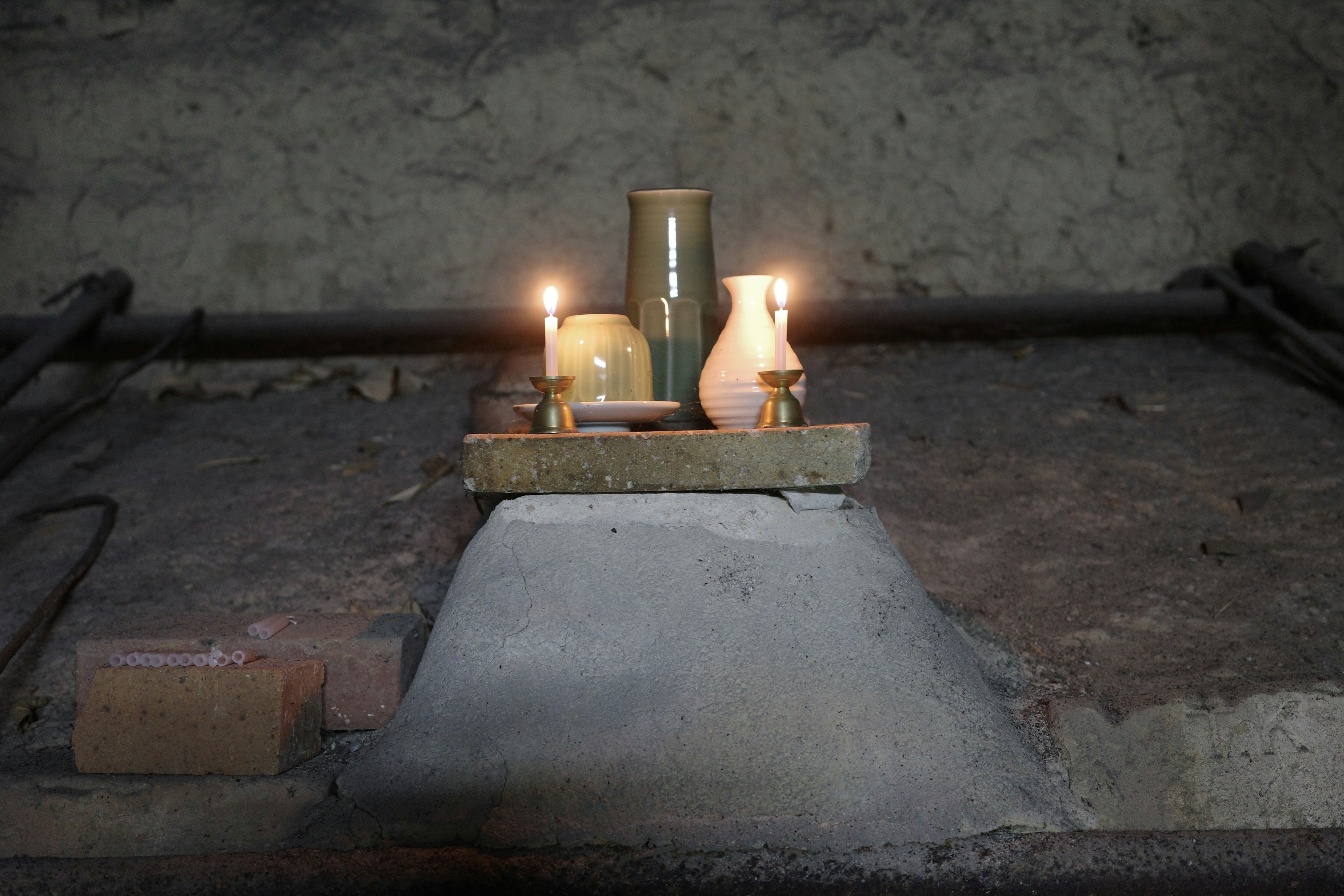 Un piccolo altare con candele e un vaso in uno spazio poco illuminato