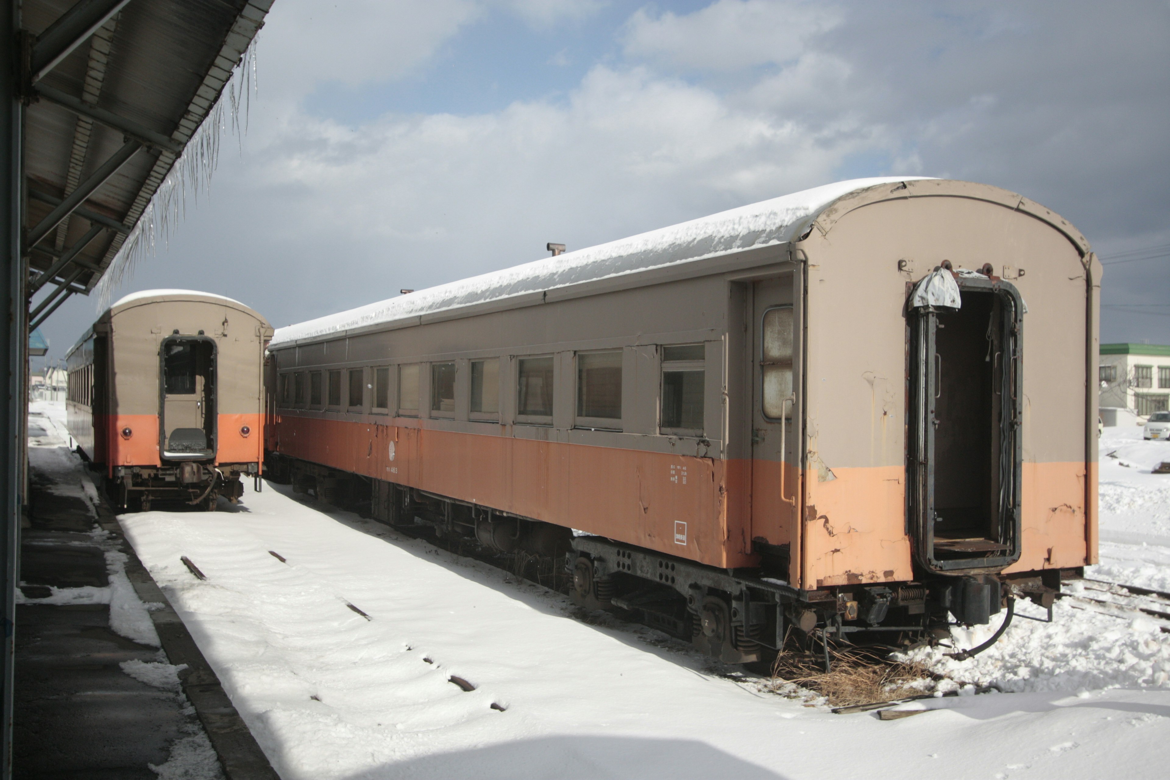 雪に覆われた駅に停車中の古い列車の車両