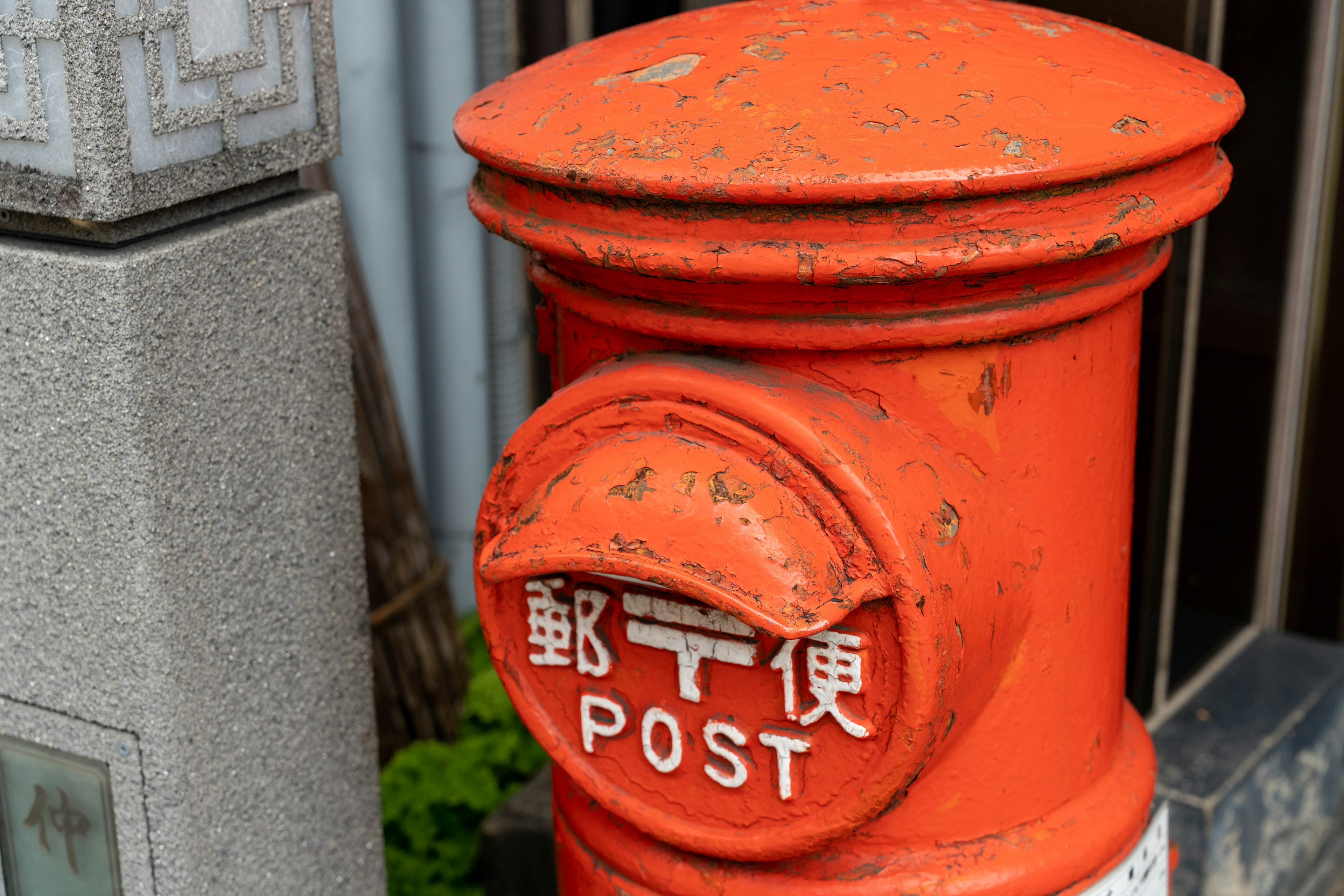 Buzón naranja con texto en inglés y japonés