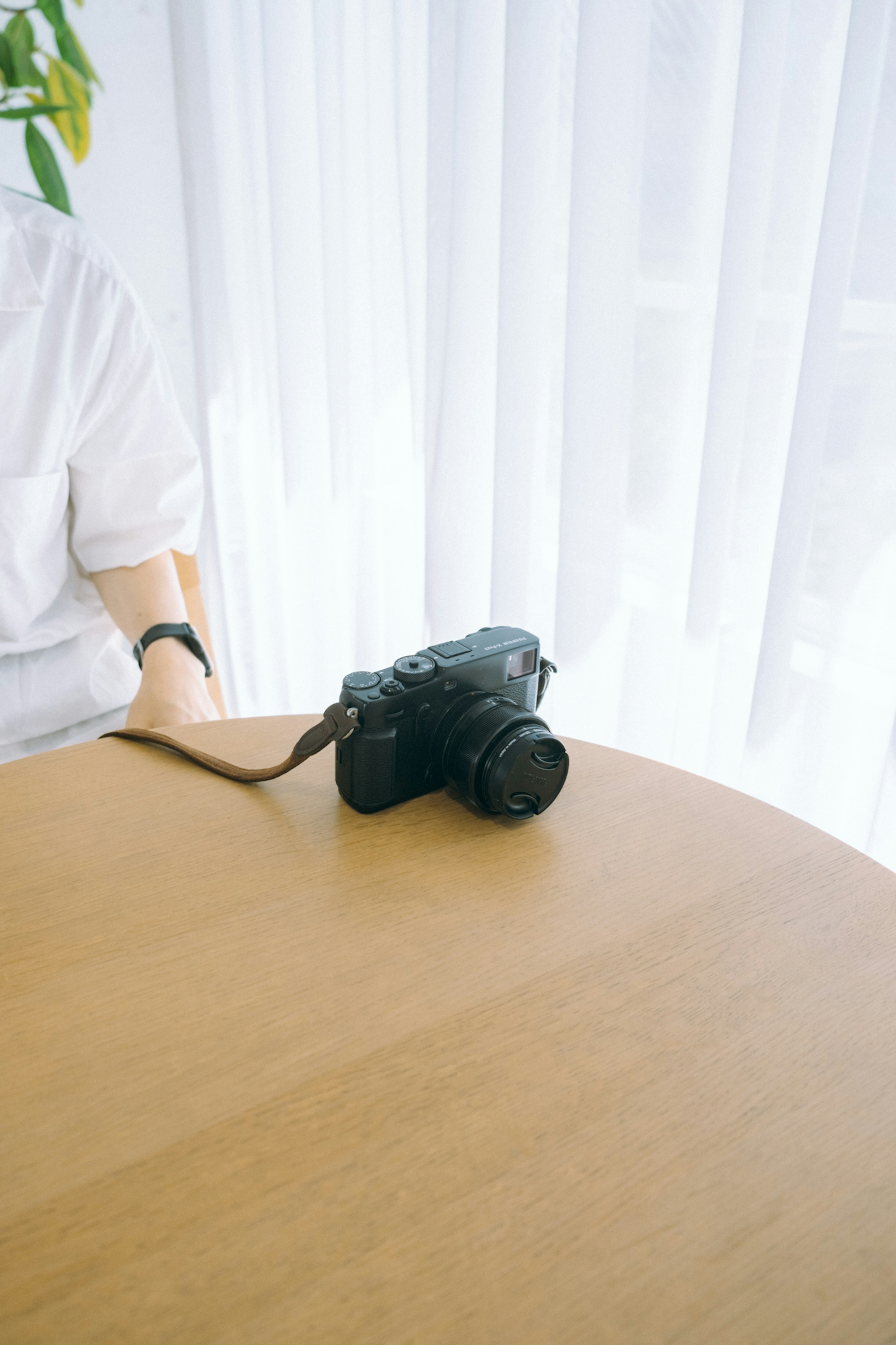 Camera placed on a wooden table with a white curtain backdrop