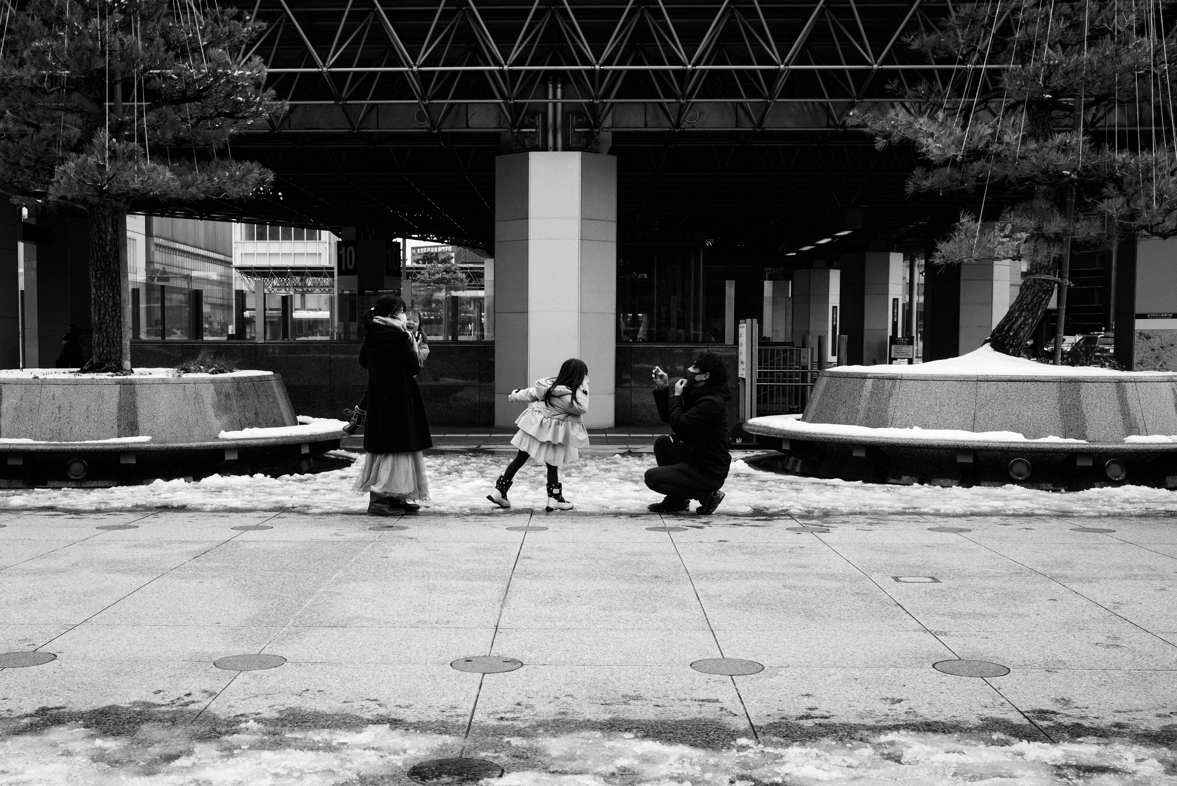 Photo en noir et blanc d'un enfant jouant dans la neige avec deux adultes