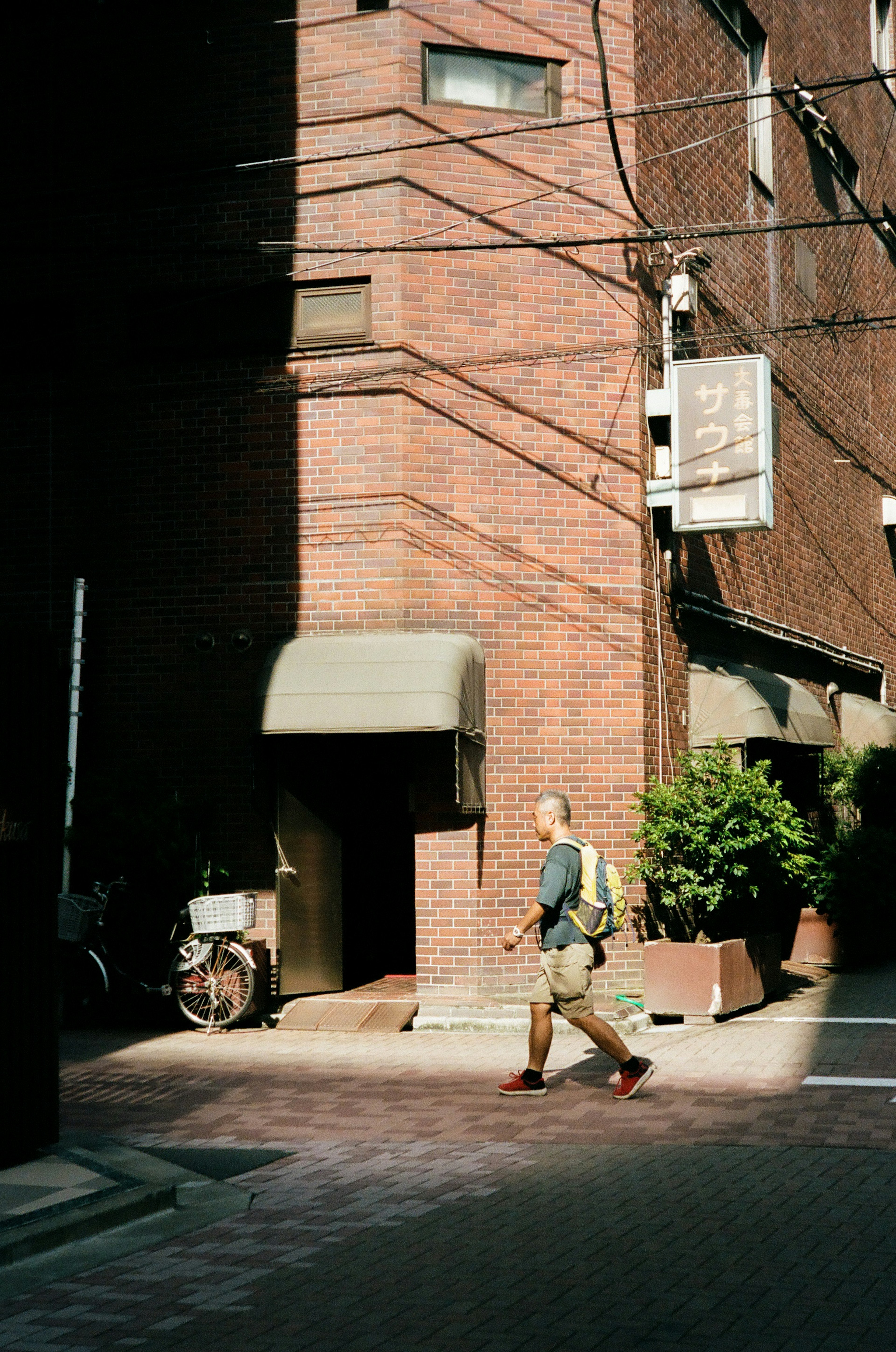 煉瓦の建物の前を歩く男性と影のある街角