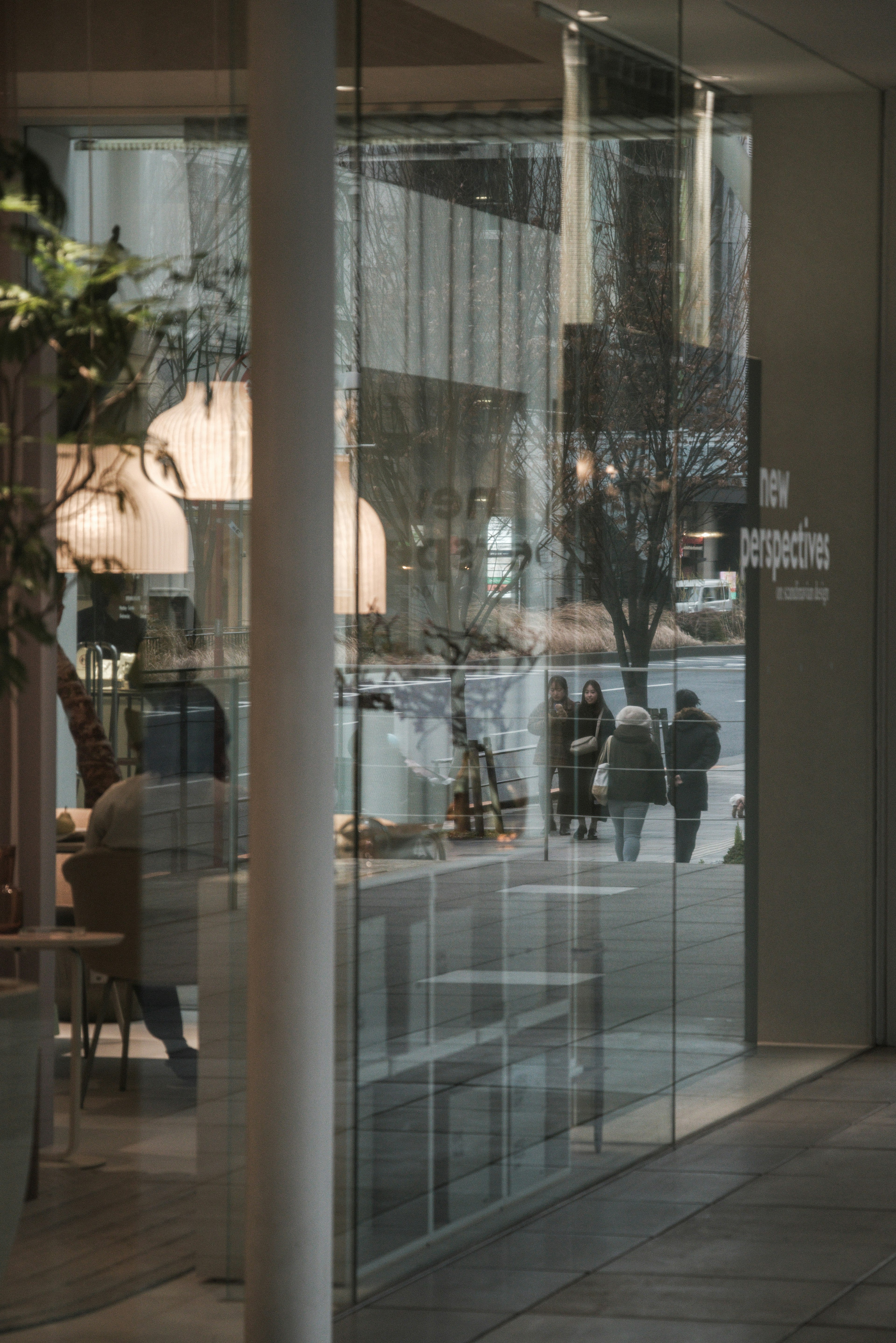 Cafe interior visible through glass wall with reflections of pedestrians