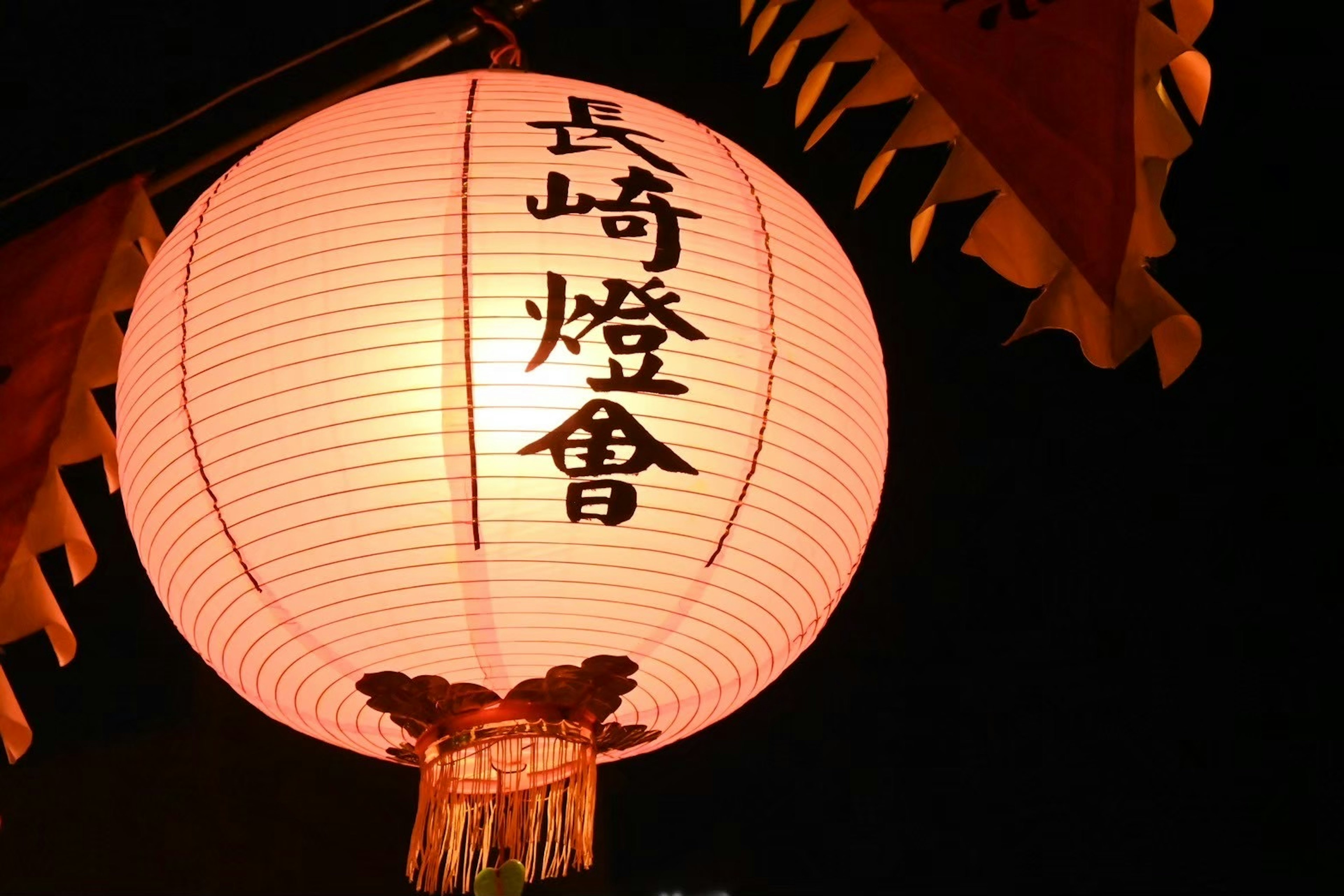 Lampion merah dengan tulisan Festival Lampion Nagasaki bercahaya di langit malam