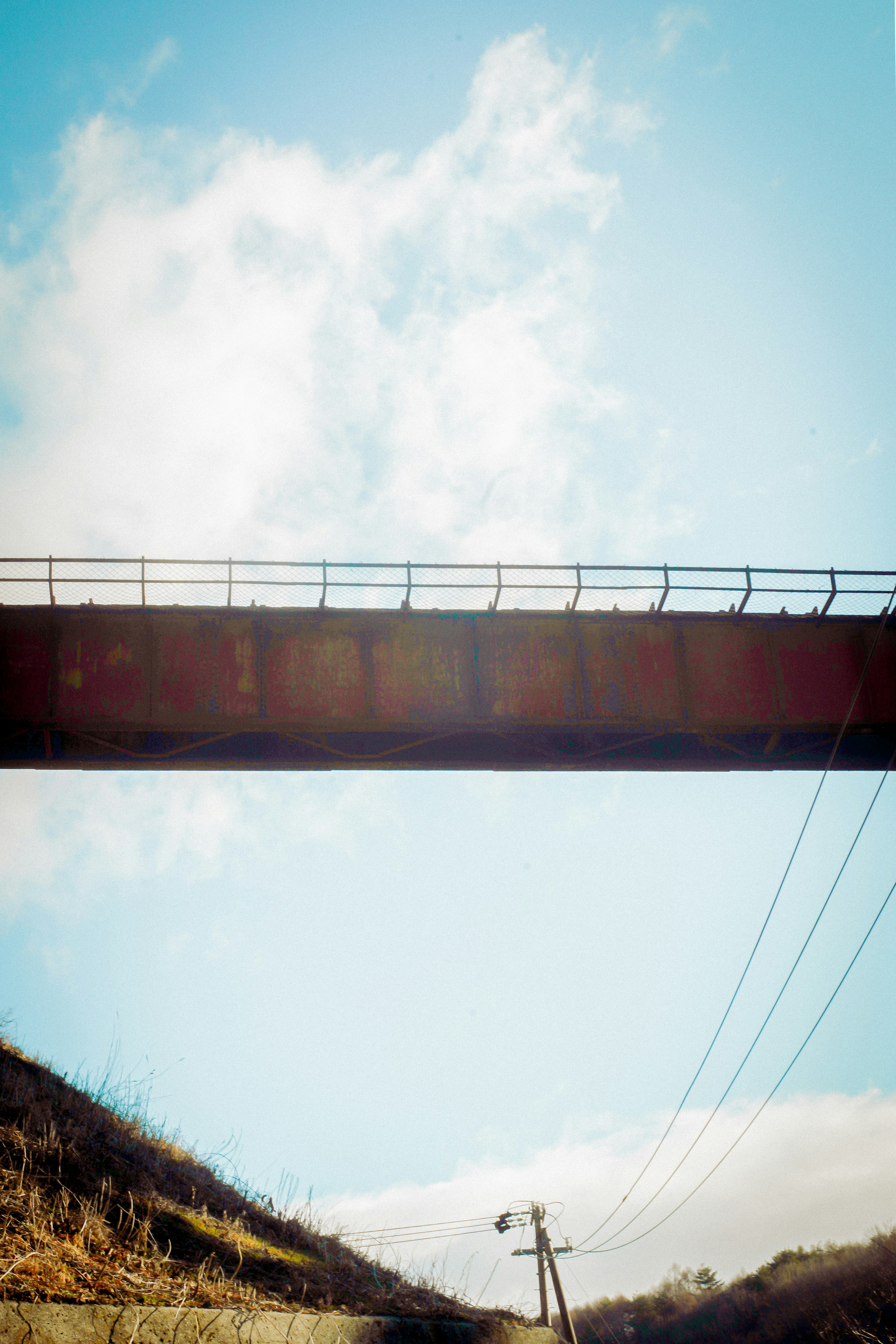 สะพานรถไฟเก่าใต้ท้องฟ้าสีฟ้าพร้อมสายไฟด้านล่าง