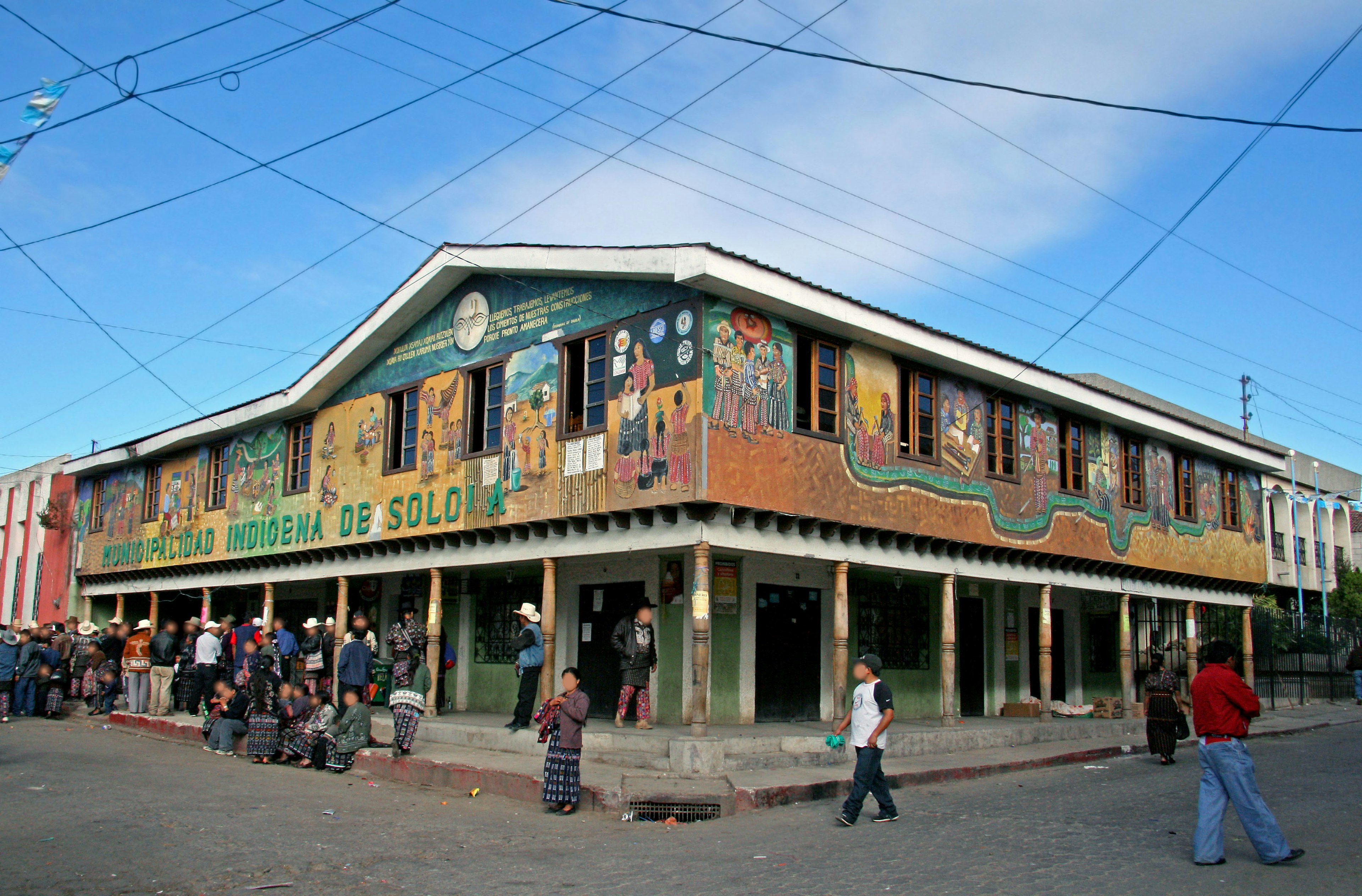 Colorful mural-covered building with people gathered around it