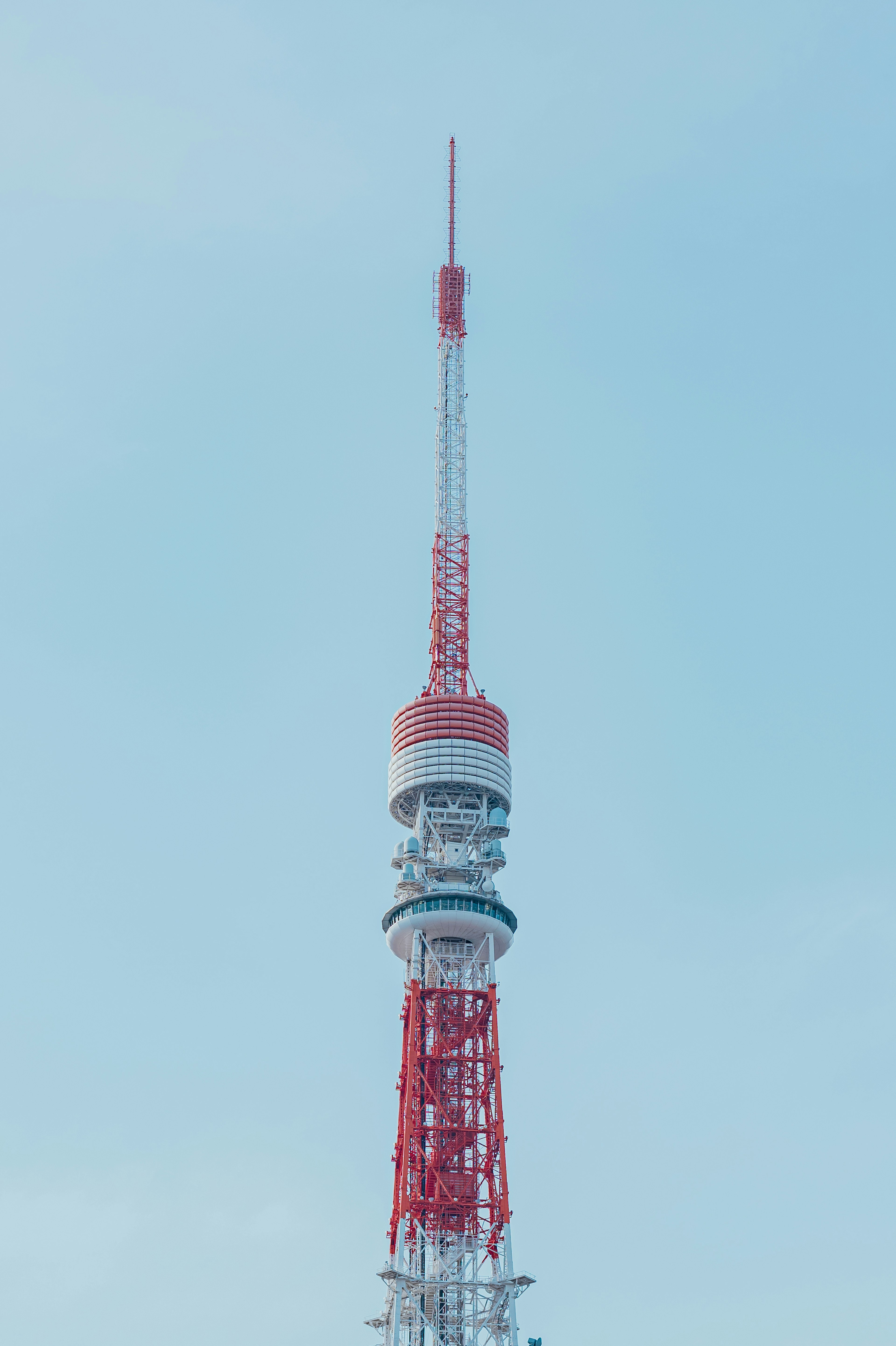 Puncak menara komunikasi merah dan putih di bawah langit biru