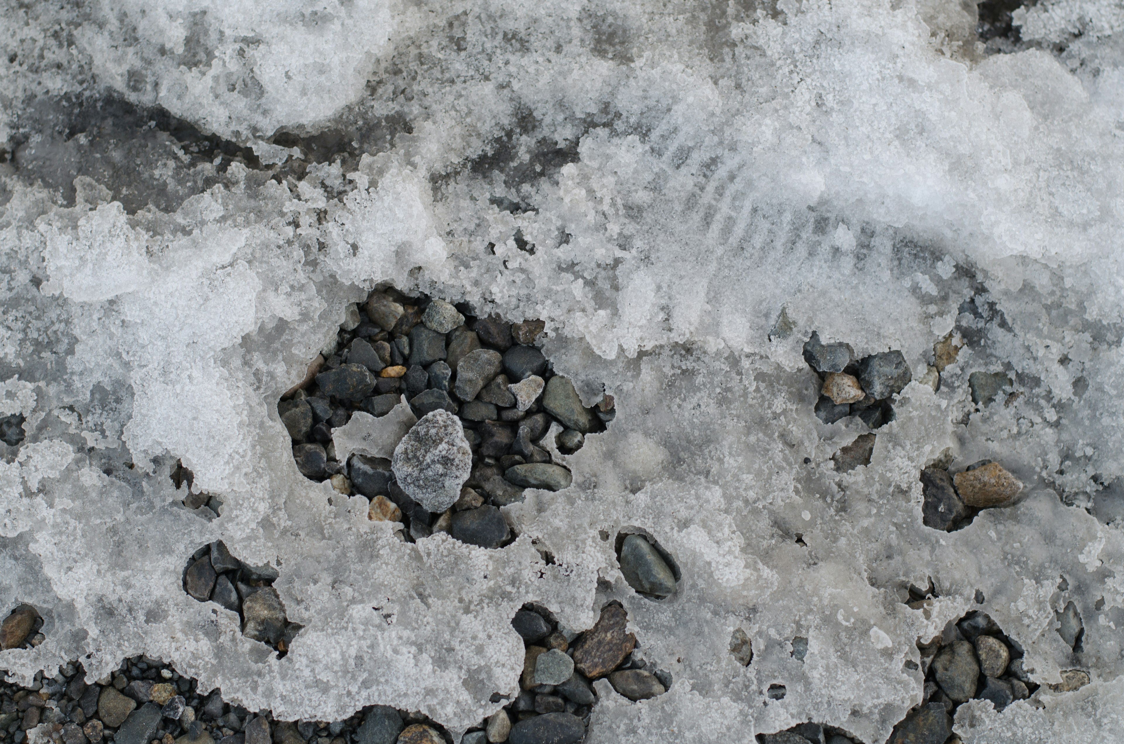 Nahaufnahme des Bodens mit Schnee und Steinen