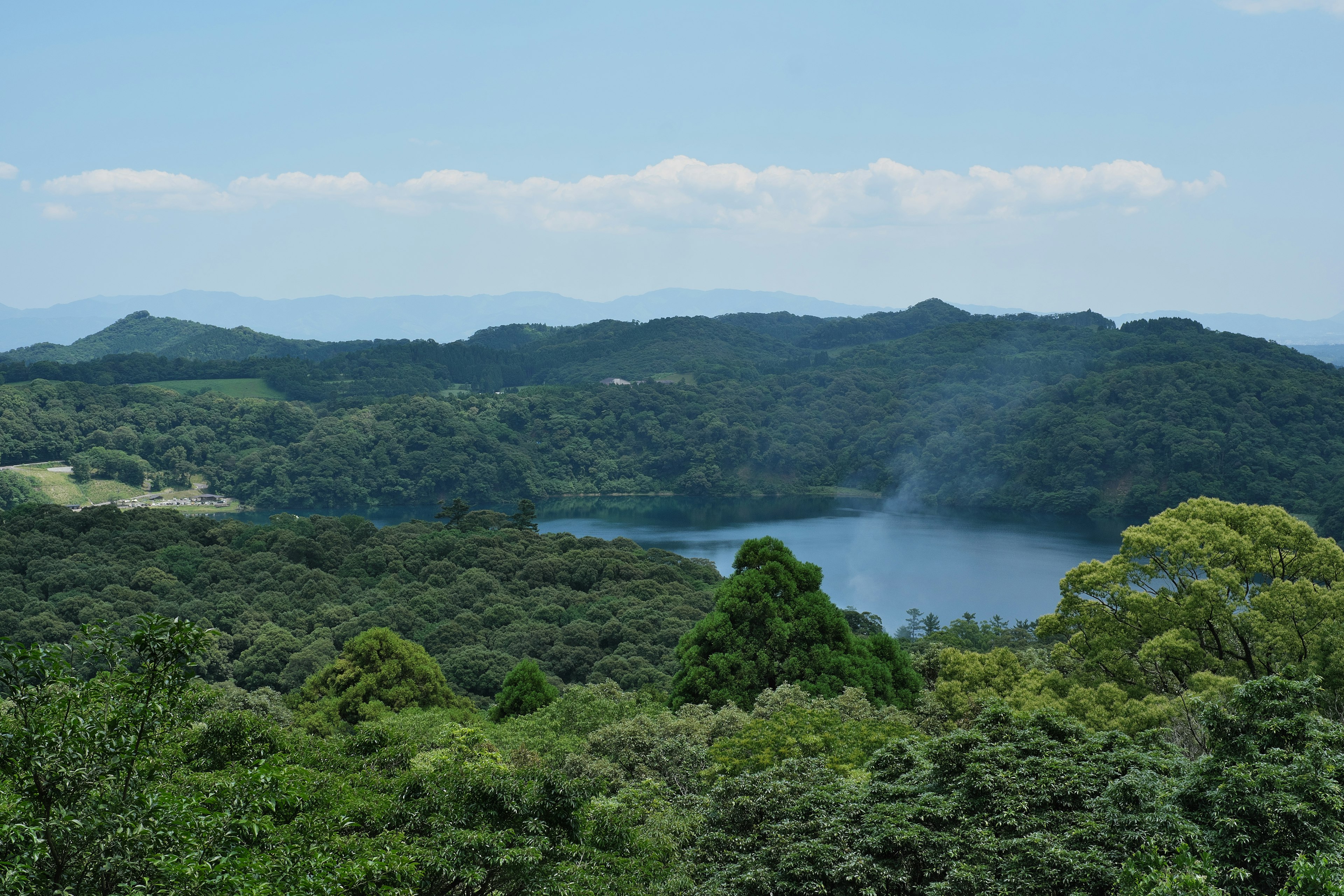 Pemandangan danau biru dikelilingi hutan lebat