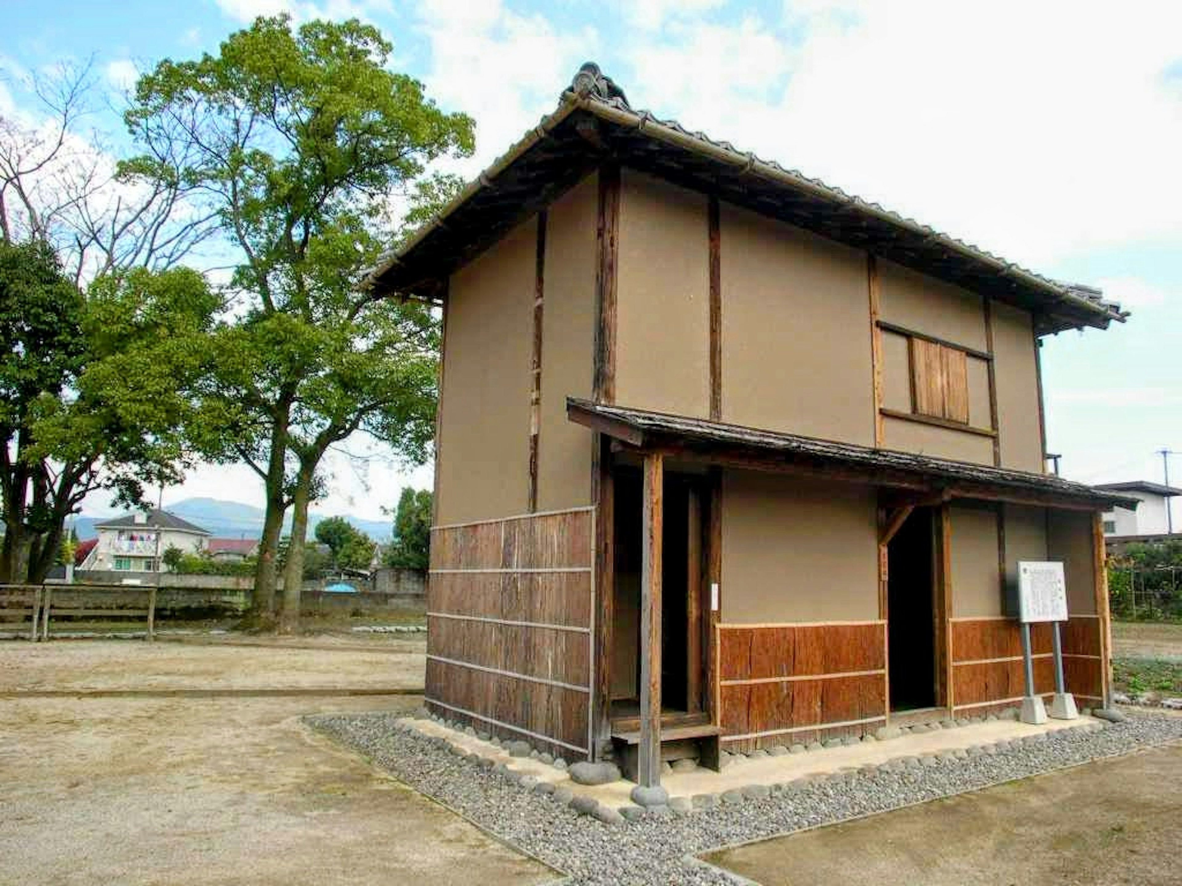 Esterno di una casa giapponese tradizionale con vegetazione lussureggiante sullo sfondo