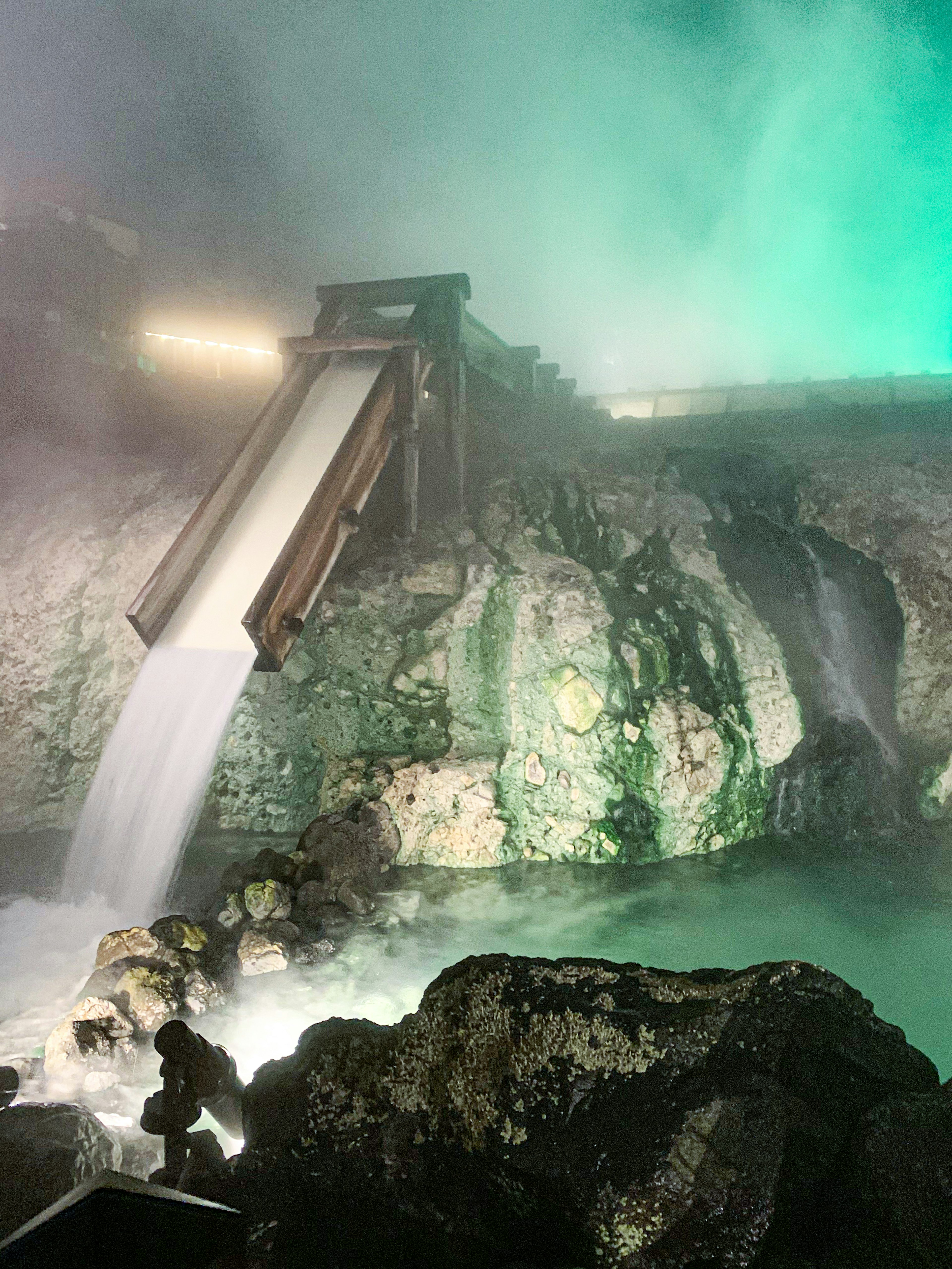 Cascata in una sorgente termale con nebbia illuminata